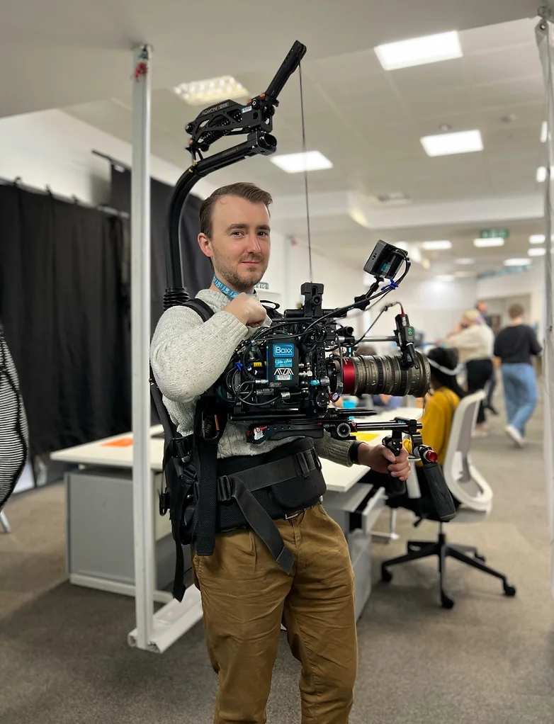 On set where the cameraman is using an Easy Rig to support his camera. 