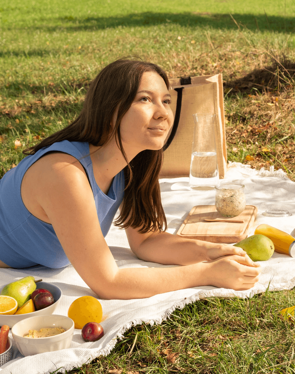 Sabrina Weimann Ernährungsberaterin liegt auf Picknickdecke mit frischem Obst und Gemüse und macht ein Picknick