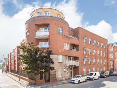 Red Mill Apartments – A red-brick apartment block with balconies and greenery.