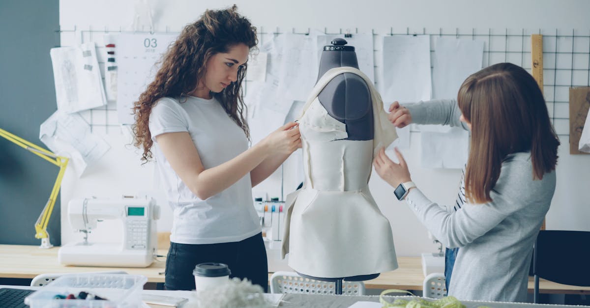 Two women design a dress in a fashion studio, showcasing creativity and teamwork.
