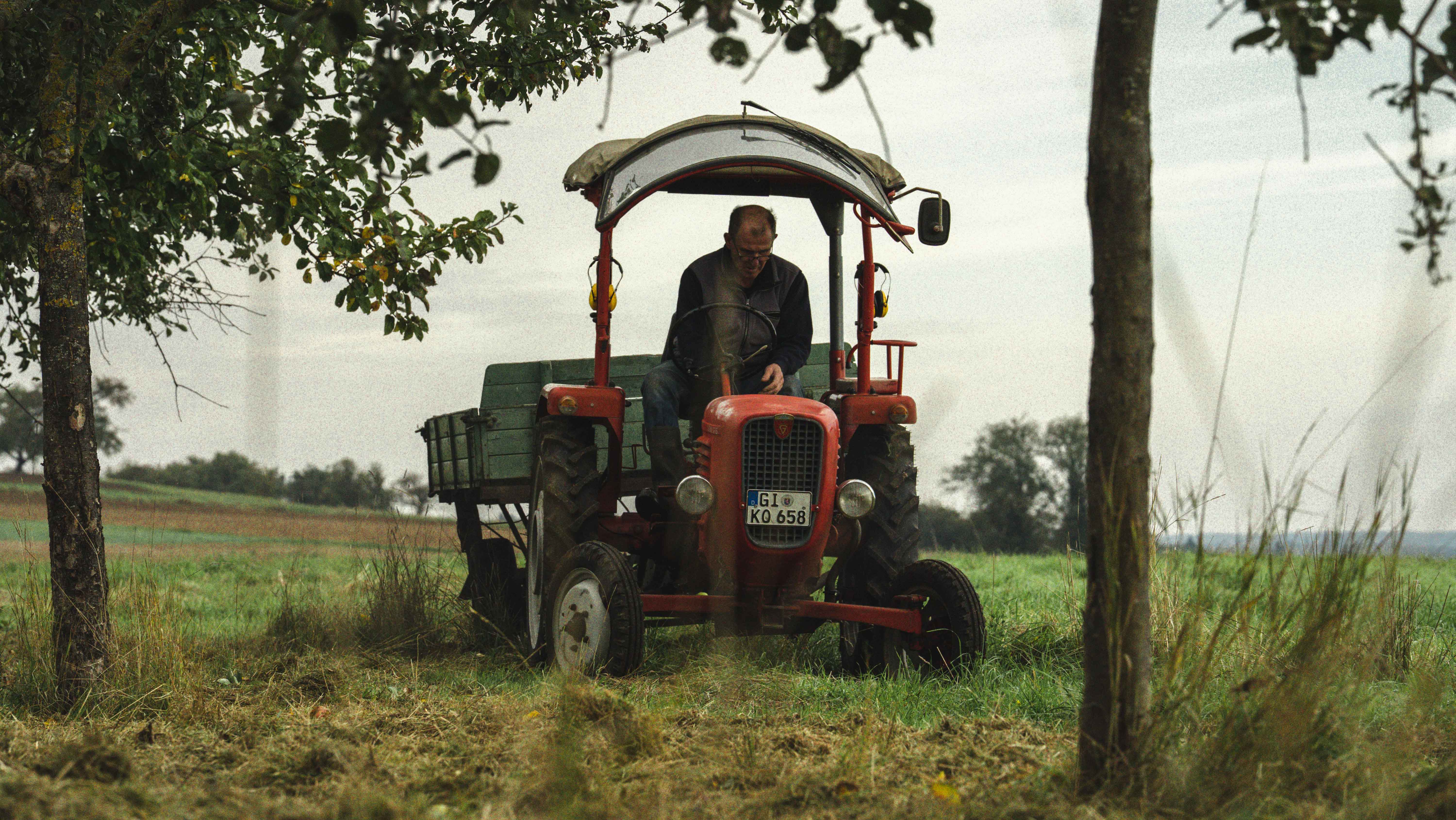 A small, dark flask is nestled among twigs and leaves on a forest floor, with a muted, mysterious ambiance.