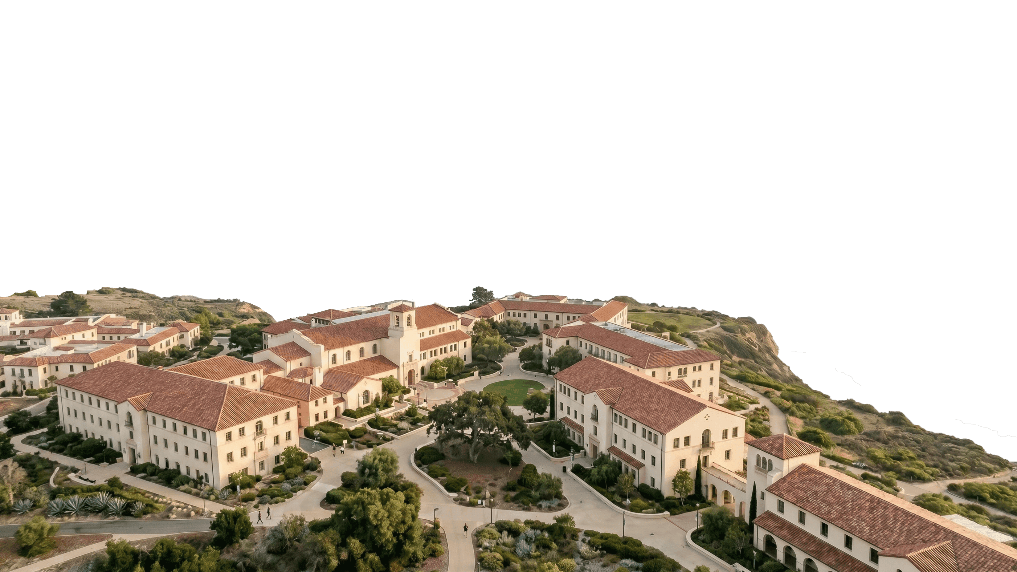 A panoramic aerial view of a picturesque coastal university campus with Spanish-style architecture, featuring terracotta-tiled roofs and beige walls, surrounded by lush greenery and scenic ocean views.