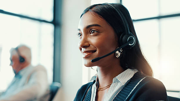 woman wearing a headset smiling in the background is a man wearing a headset