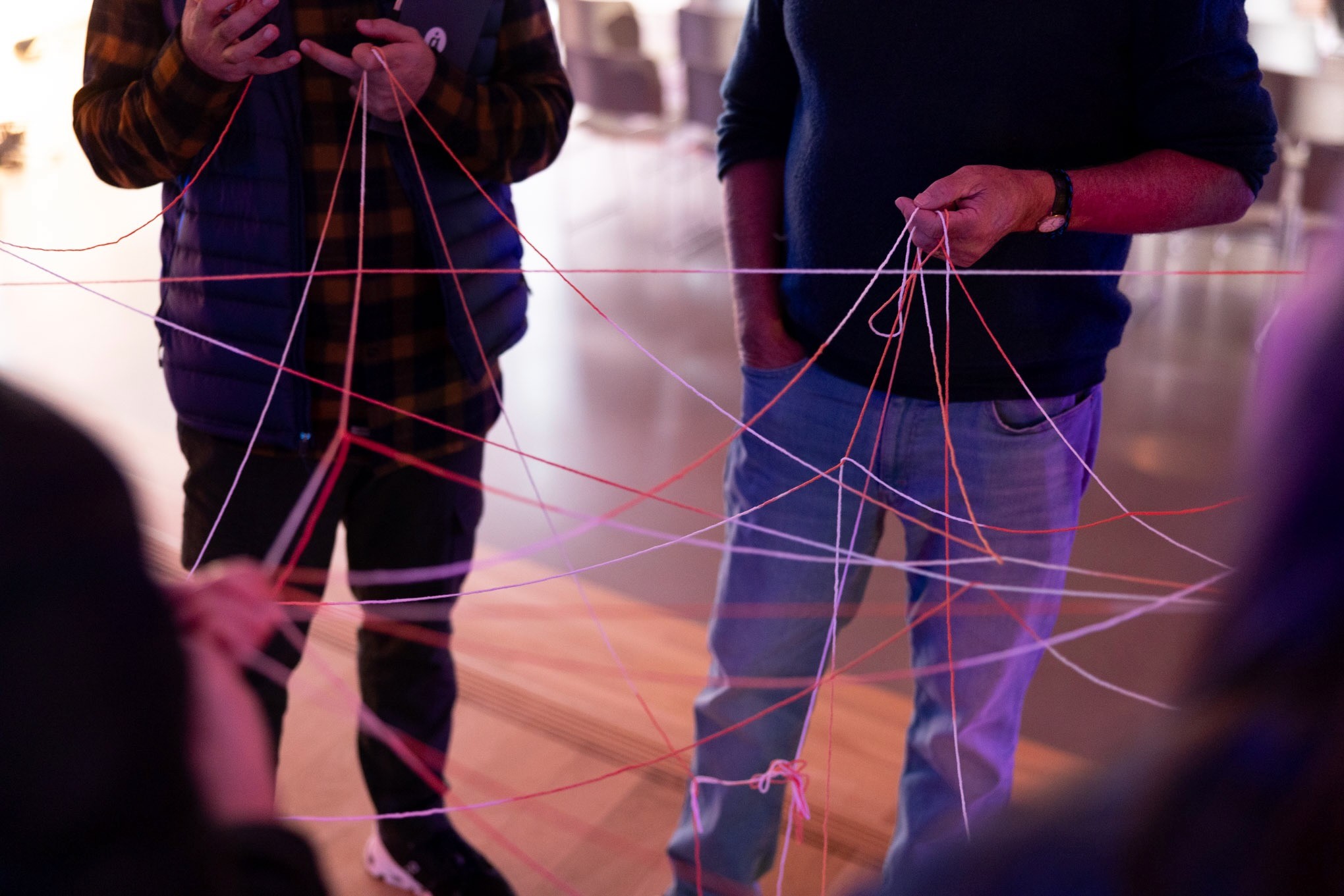 Three people holding string organized as a web between them at the Artificiality Summit