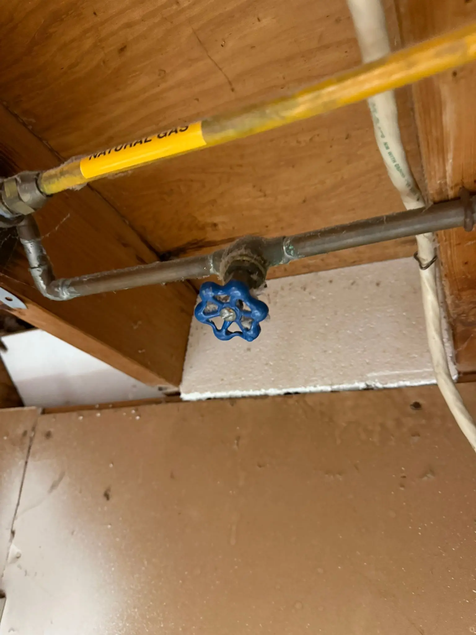A clearly labeled yellow natural gas pipe and a blue safety shutoff valve, inspected during a professional gas line repair service.