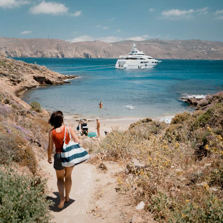 Superyacht anchored beyond a rocky cove and beach in the Greek islands, TERAMOK production