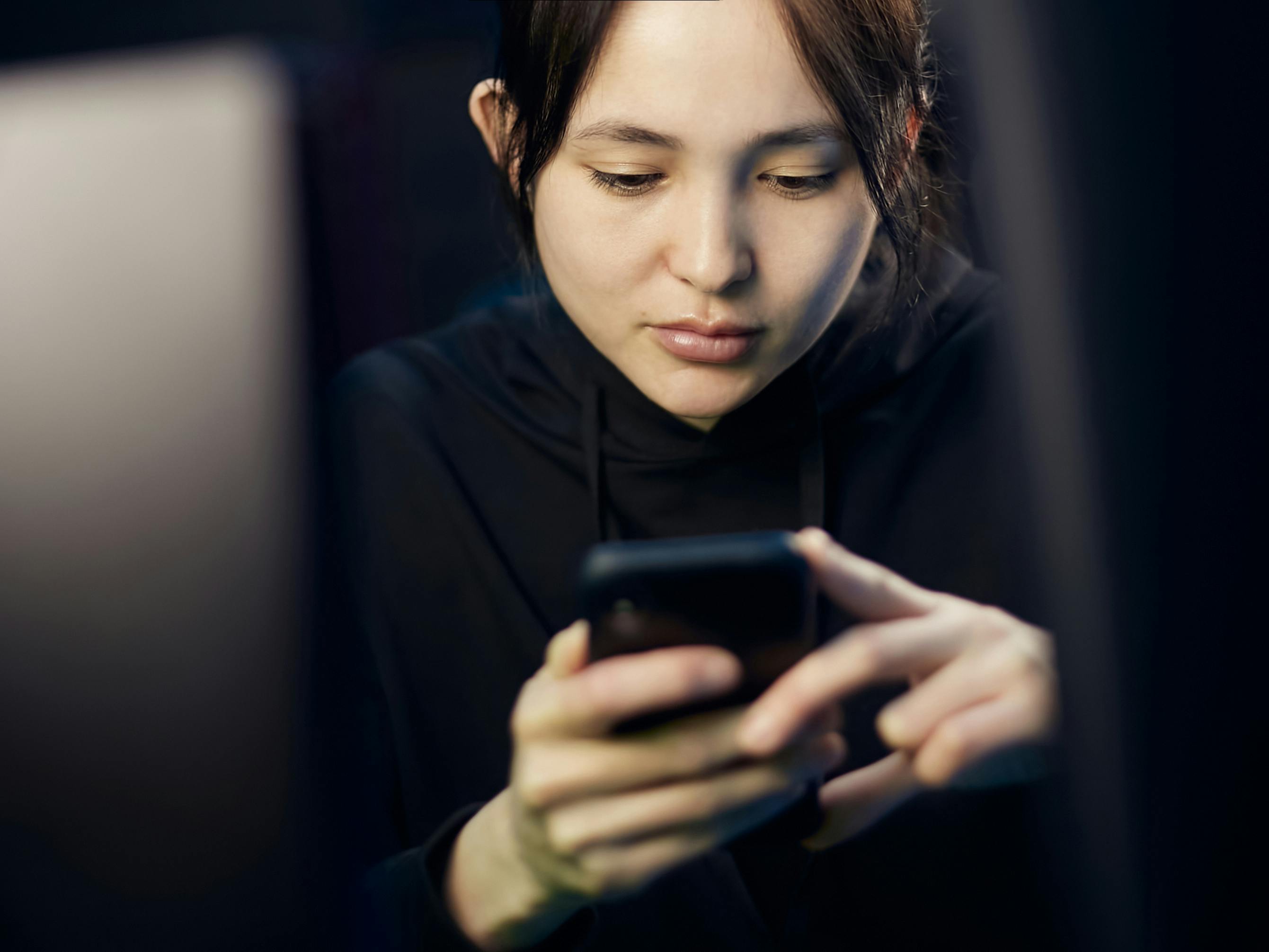 person scrolling phone addicted social media dark room