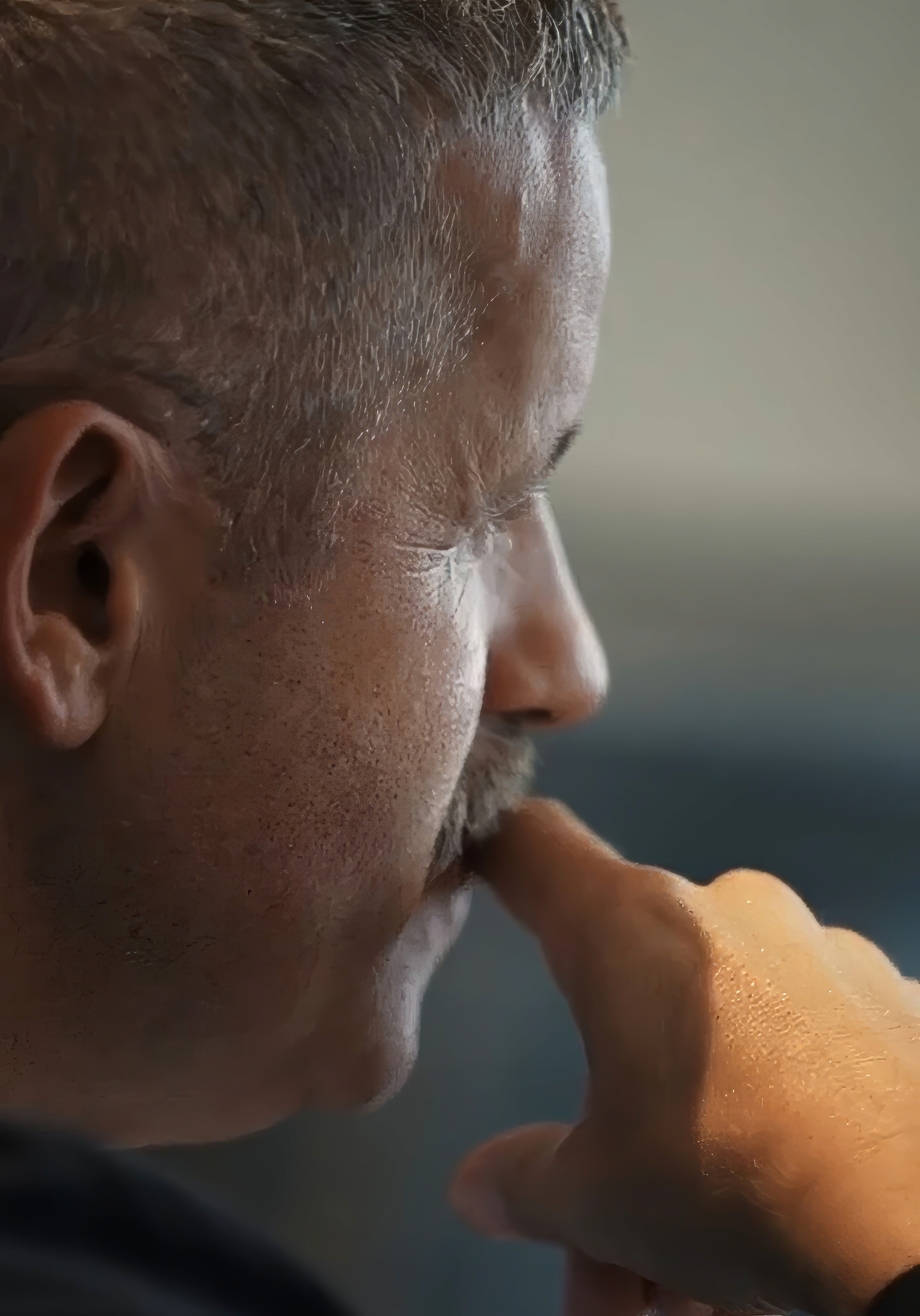 Bride sitting on ground against wall, groom standing nearby