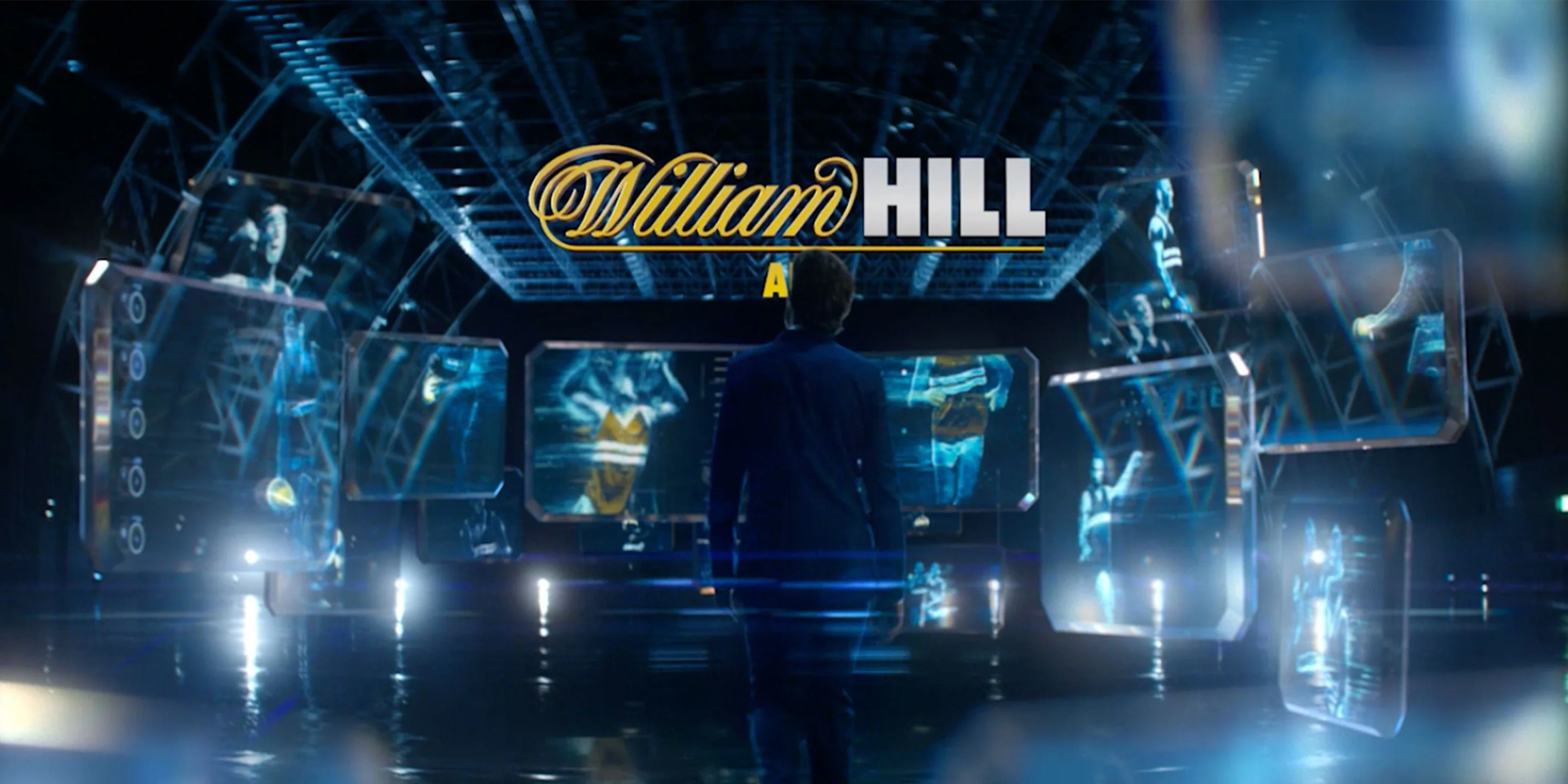 William Hill logo above a man facing a futuristic studio of glowing holographic screens, from 'Meet Axel Whitehead'