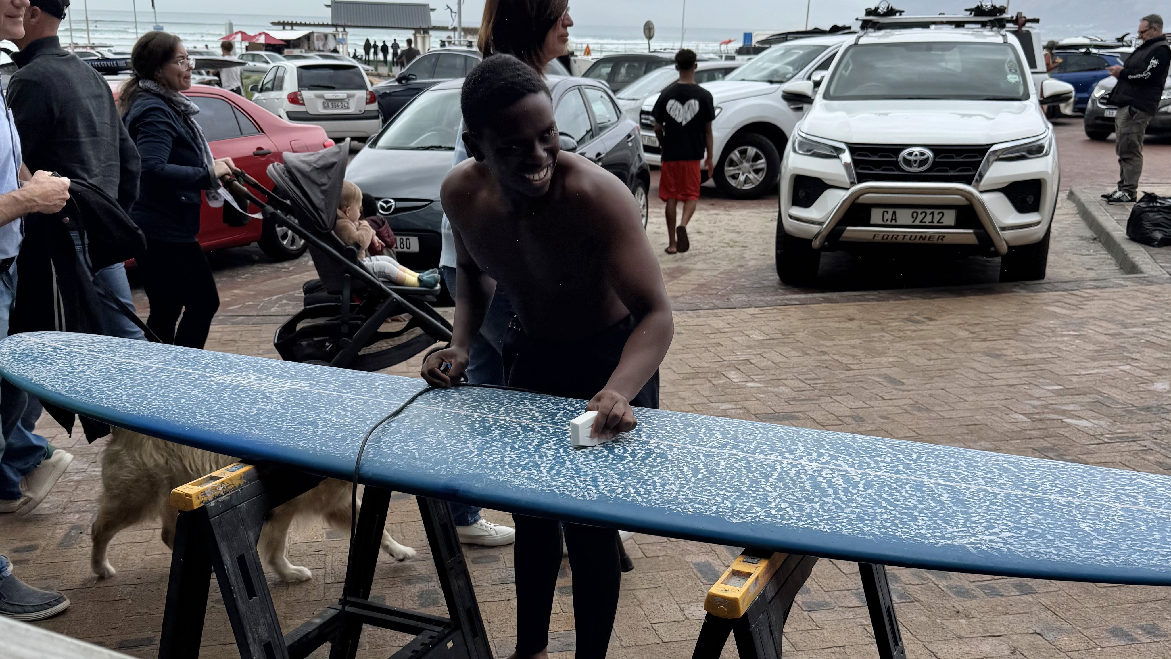 Male surfer waxing his longboard before going into the ocean for a surf session