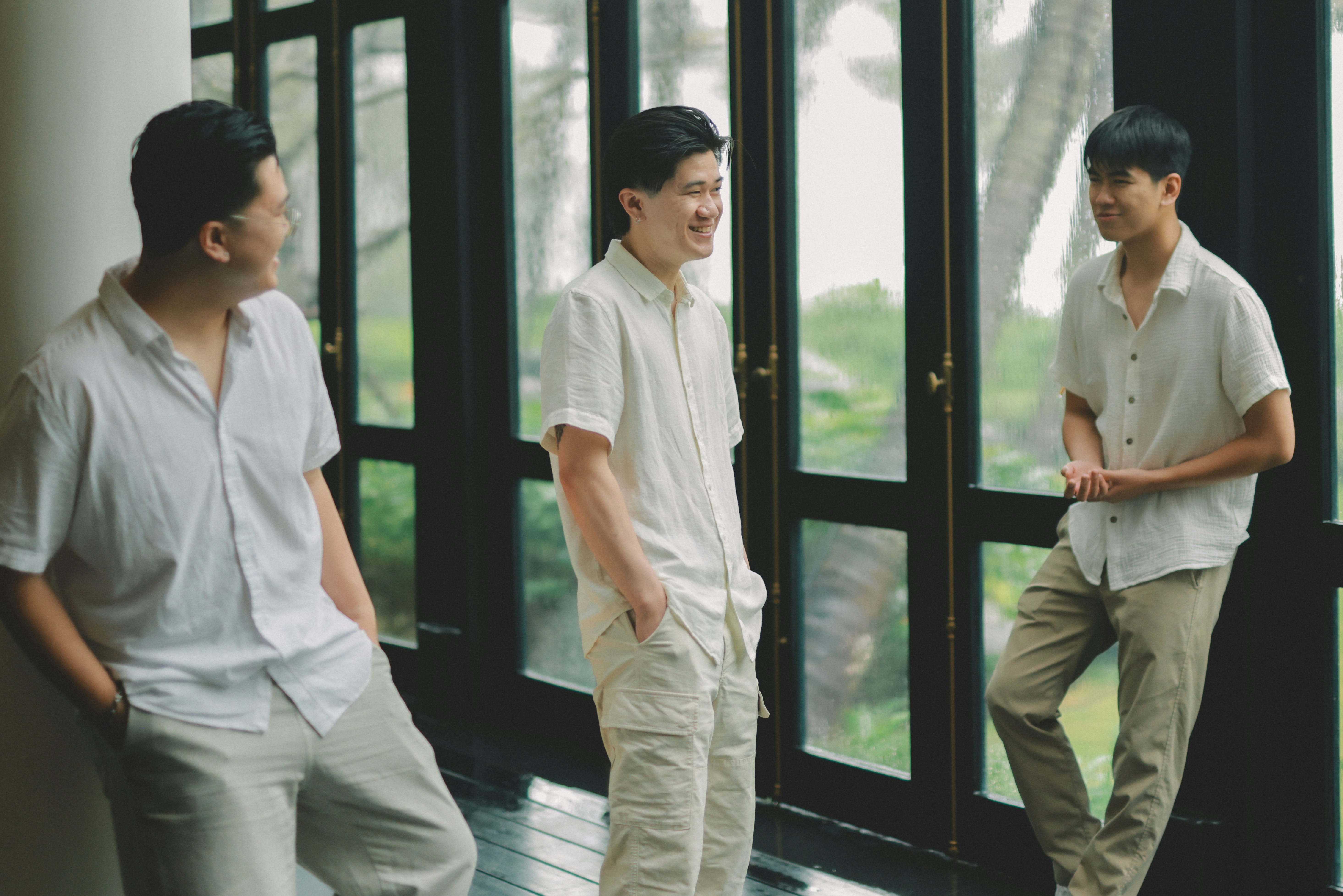 Three men standing by a large window