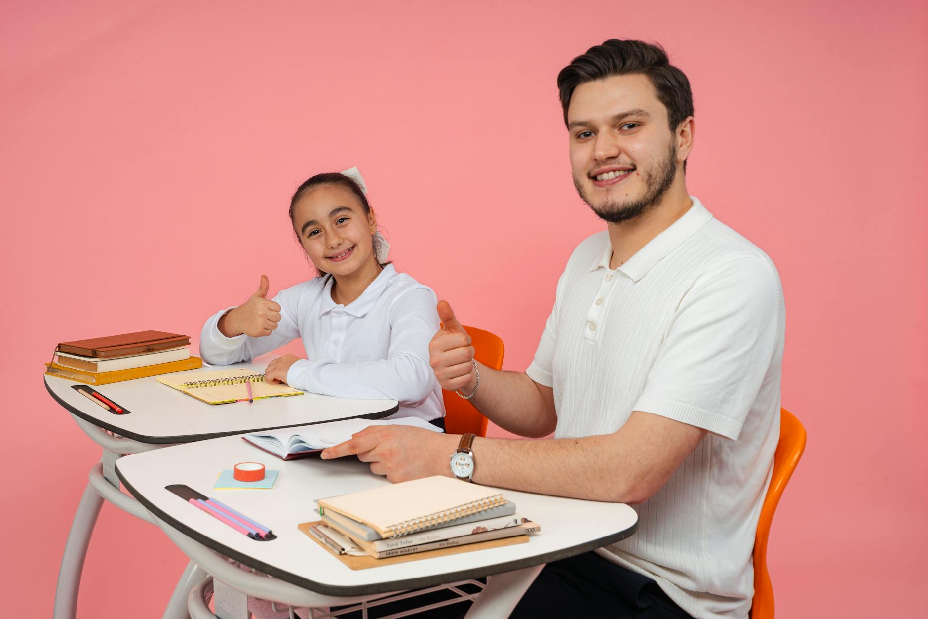 Teacher kneeling beside a student's desk to give quiet, positive feedback during an independent writing activity.