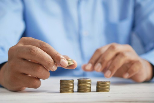 Close-up of a person stacking coins on a table, representing payment deposits and revenue protection for businesses