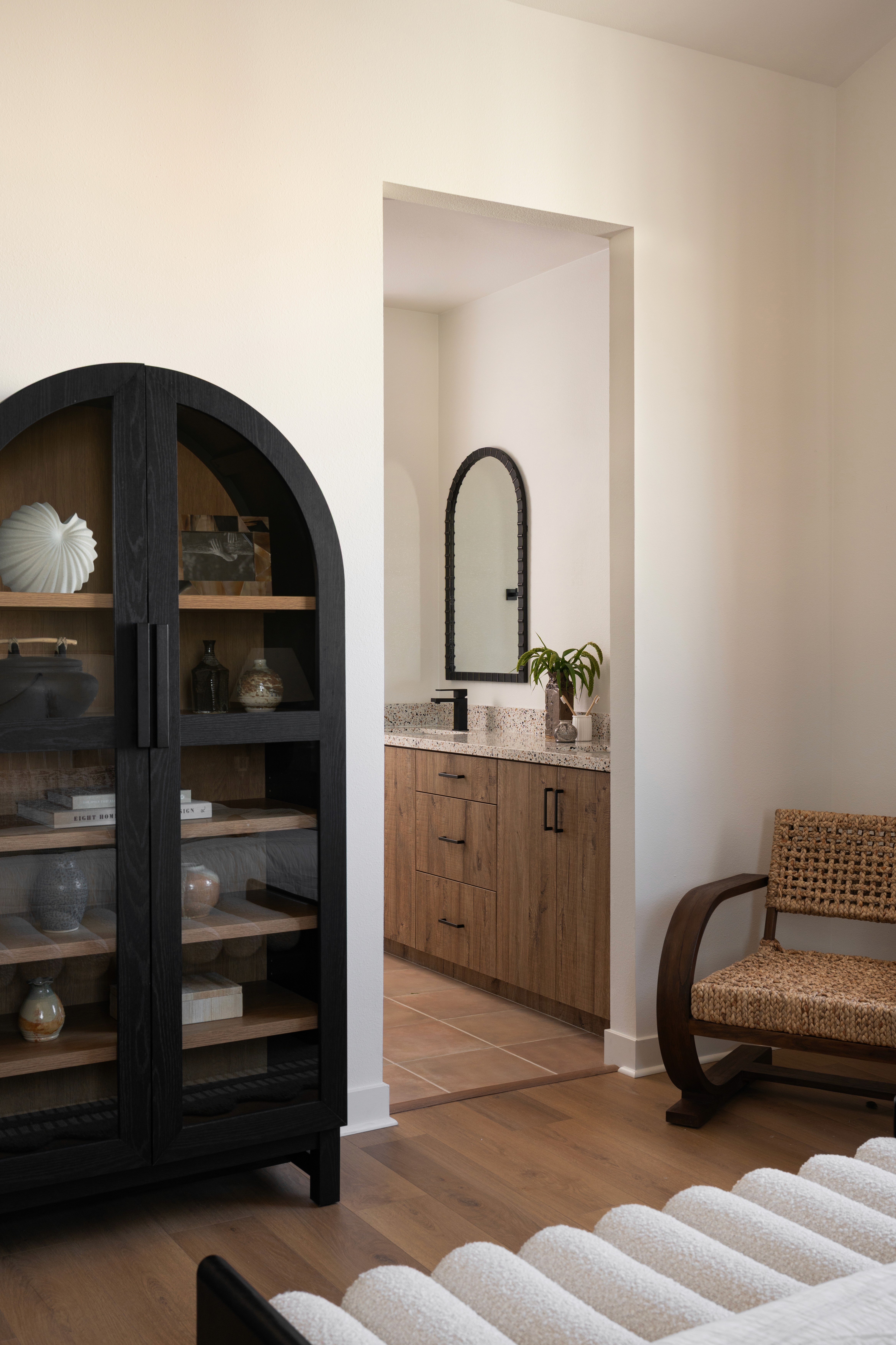 Primary bedroom cabinet, chair and view into bathroom