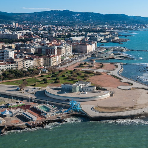 一个沿海城市的鸟瞰图，展示了建筑物、道路、公园以及伴随有步行道的土耳其蓝海岸线。