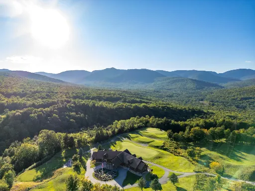 Aerial view of a mountain lodge and golf course at sunrise