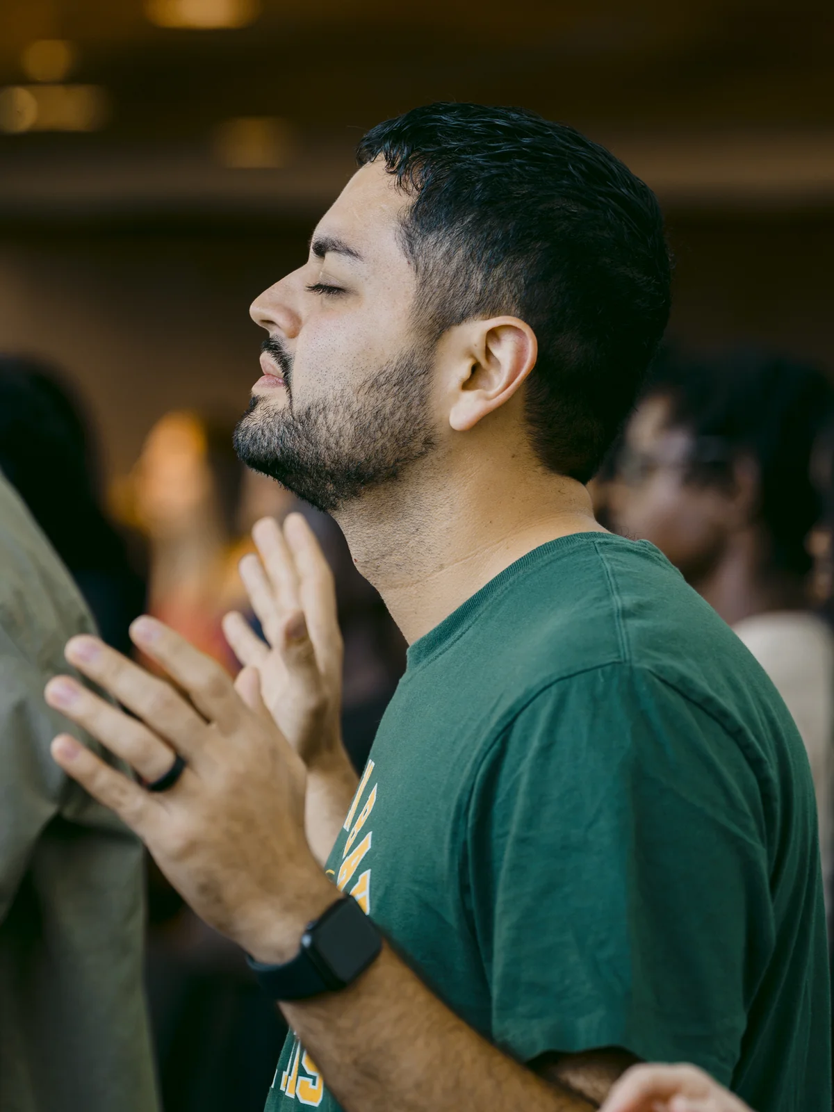 Man worshipping with eyes closed and hands together during a Sunday service at Elan Church in Naperville