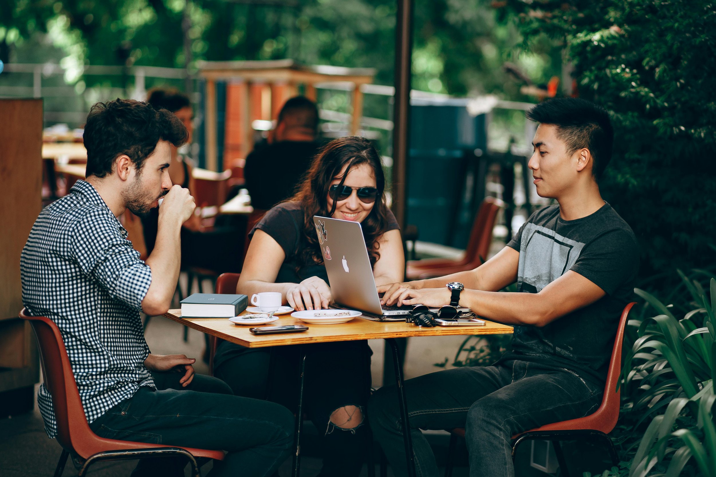 Three people sitting and working at a coffeeshop.