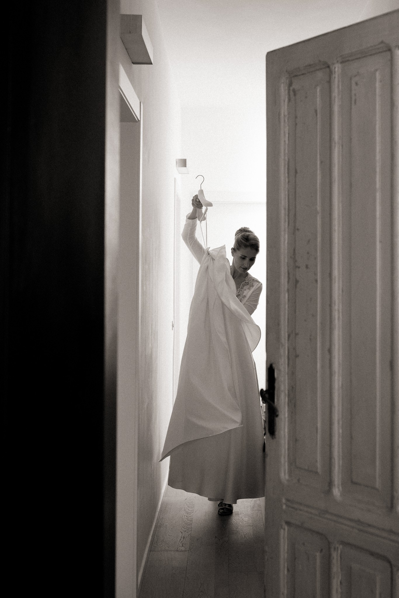 Sposa ai preparativi solleva il velo bianco in corridoio luminoso di Villa Malenchini, reportage di matrimonio