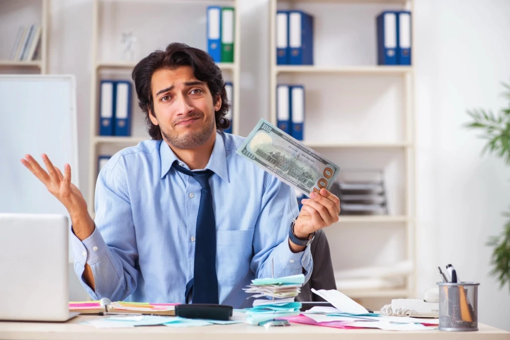 Male hold a large $100 bill, making a gesture with his hands.