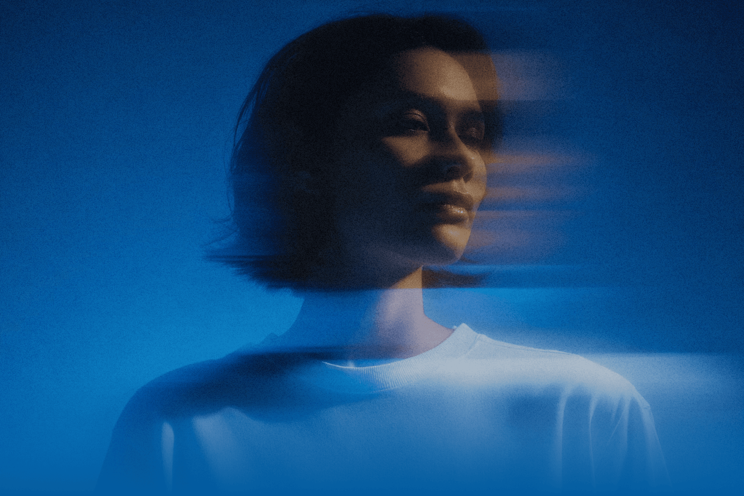  A woman dressed in a white shirt is set against a vibrant blue background.