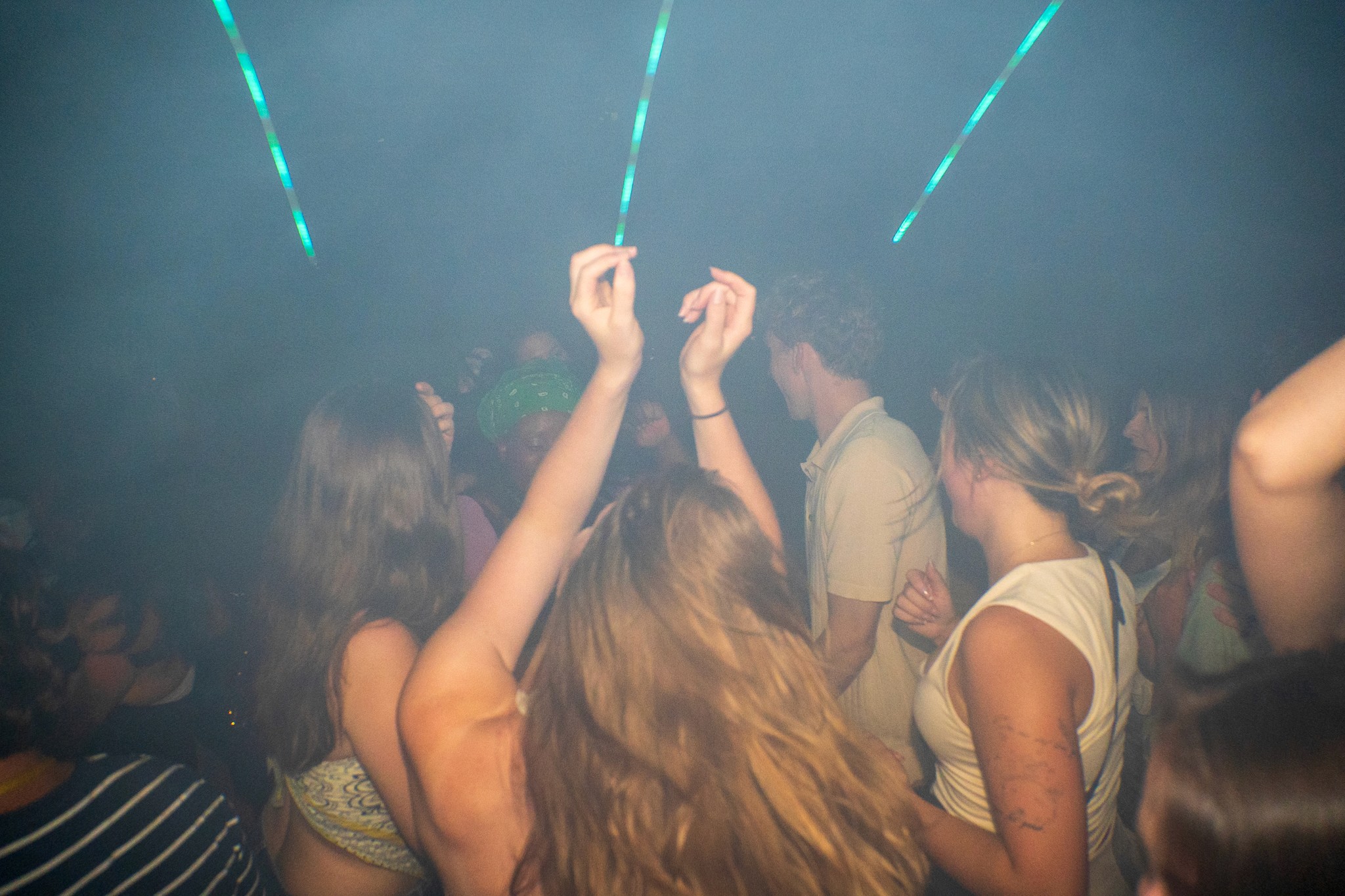 Crowd dancing inside a smoky nightclub during a bar crawl in Nice with arms raised neon ceiling lights and intense club atmosphere capturing peak party energy and immersive nightlife vibes on the French Riviera