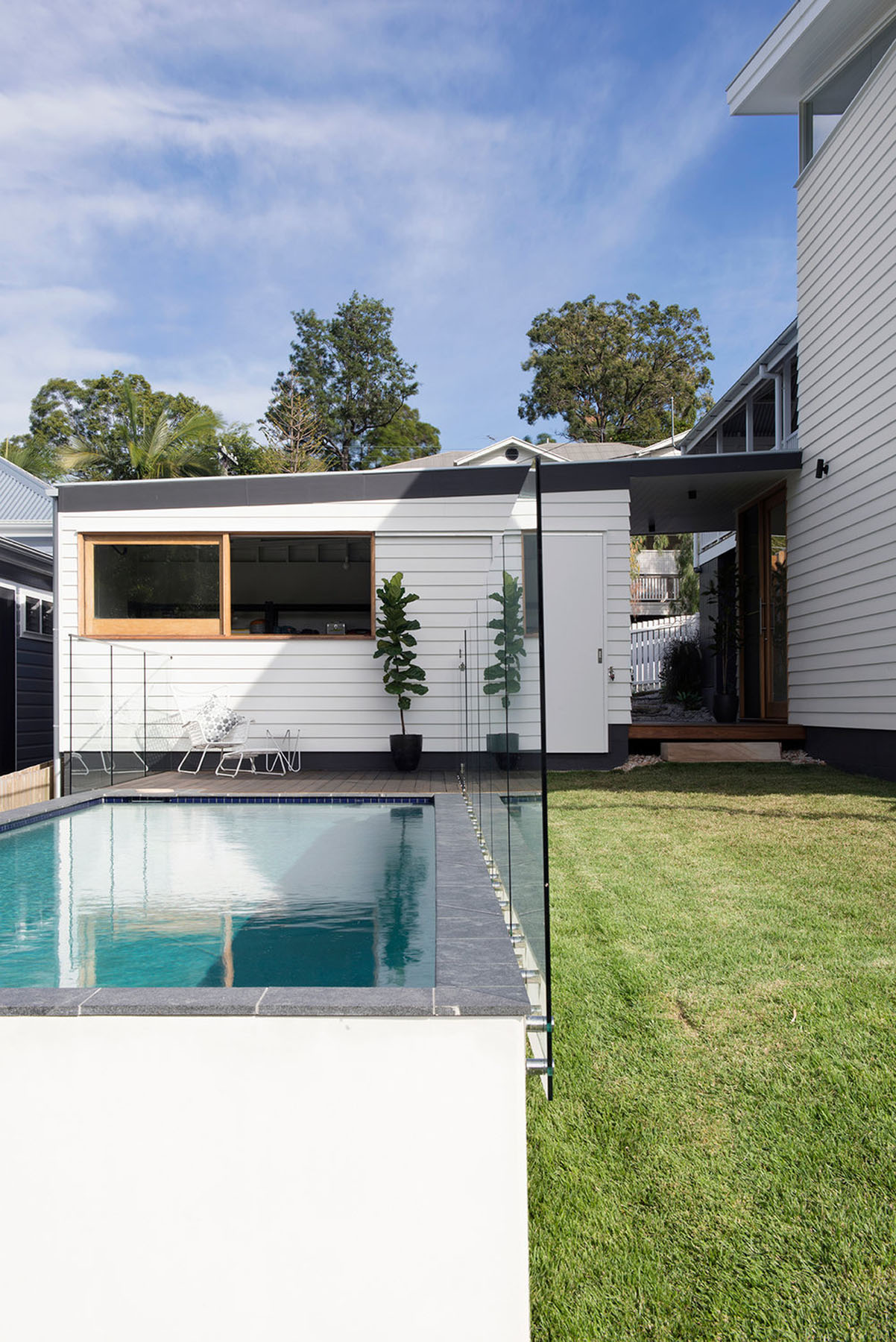 Rear extension with gabled roofline, timber-framed openings, and poolside courtyard connecting old and new volumes.