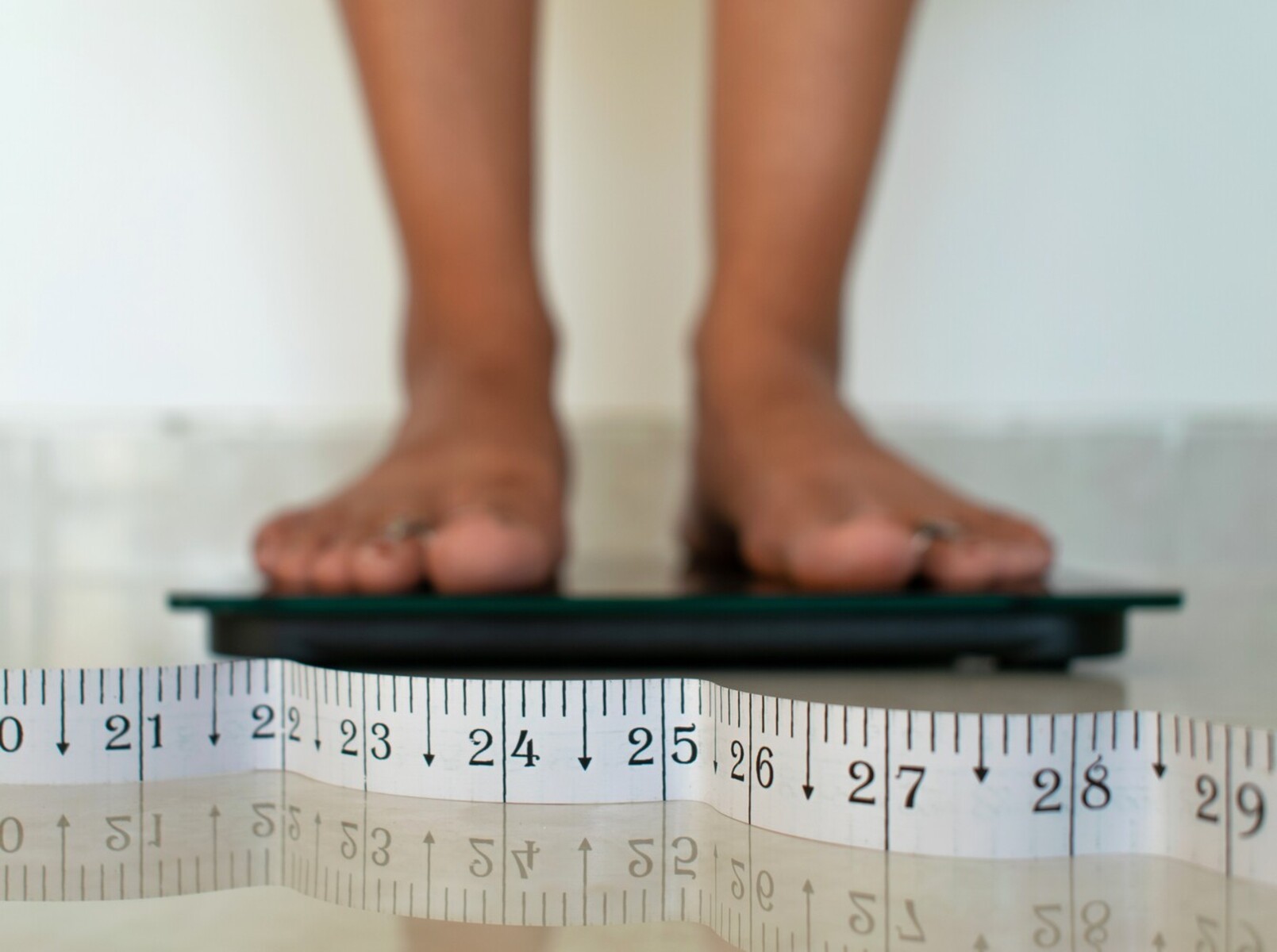 woman standing on a scale at home to check her results from learning how to lose weight walking