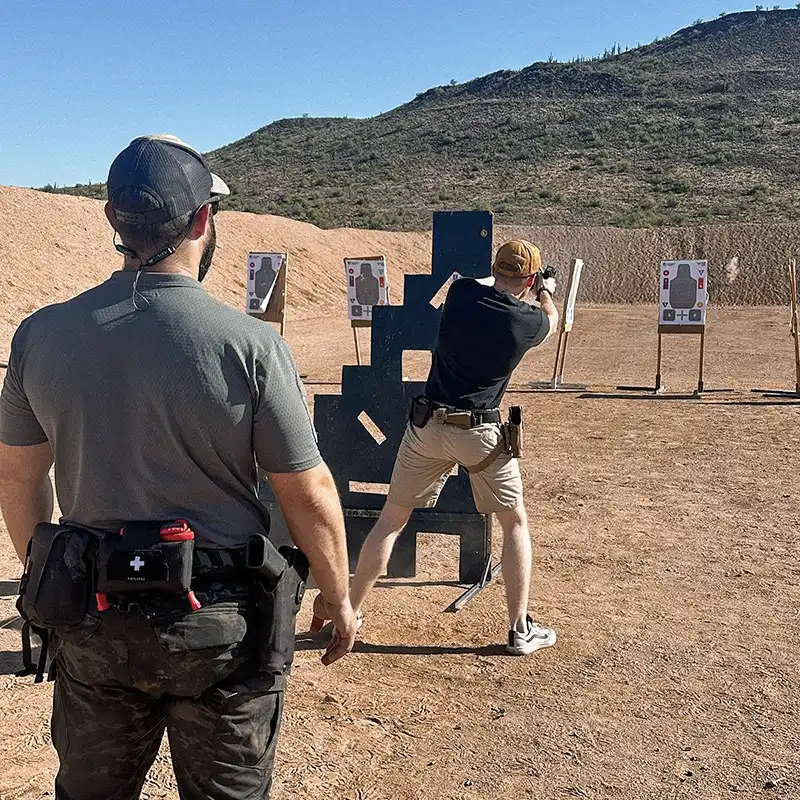 Professional tactical training exercise demonstrating dynamic shooting positions and instructor supervision