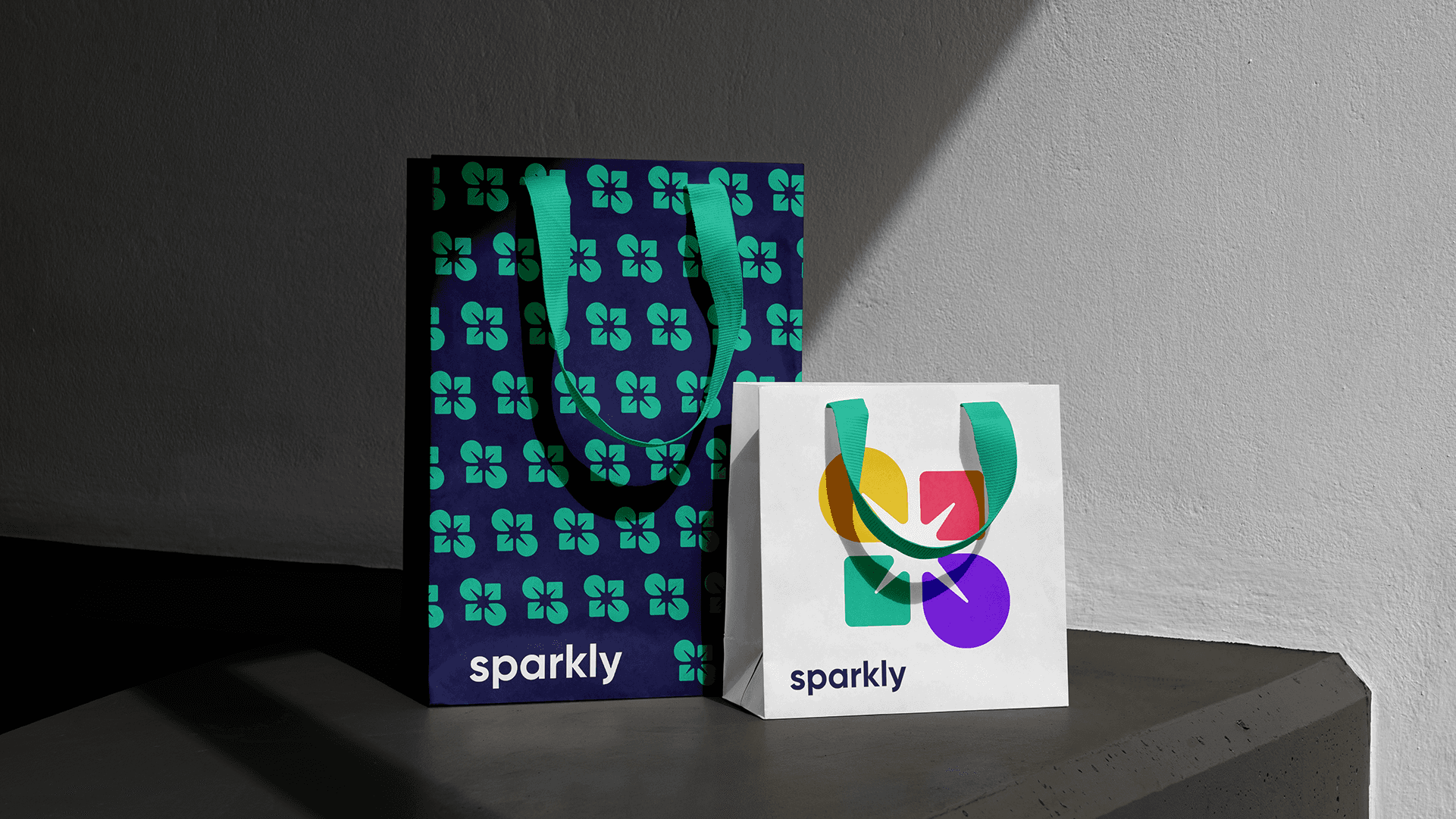 Two Sparkly shopping bags: a navy bag with a teal logo pattern and a white bag with a large colorful logomark