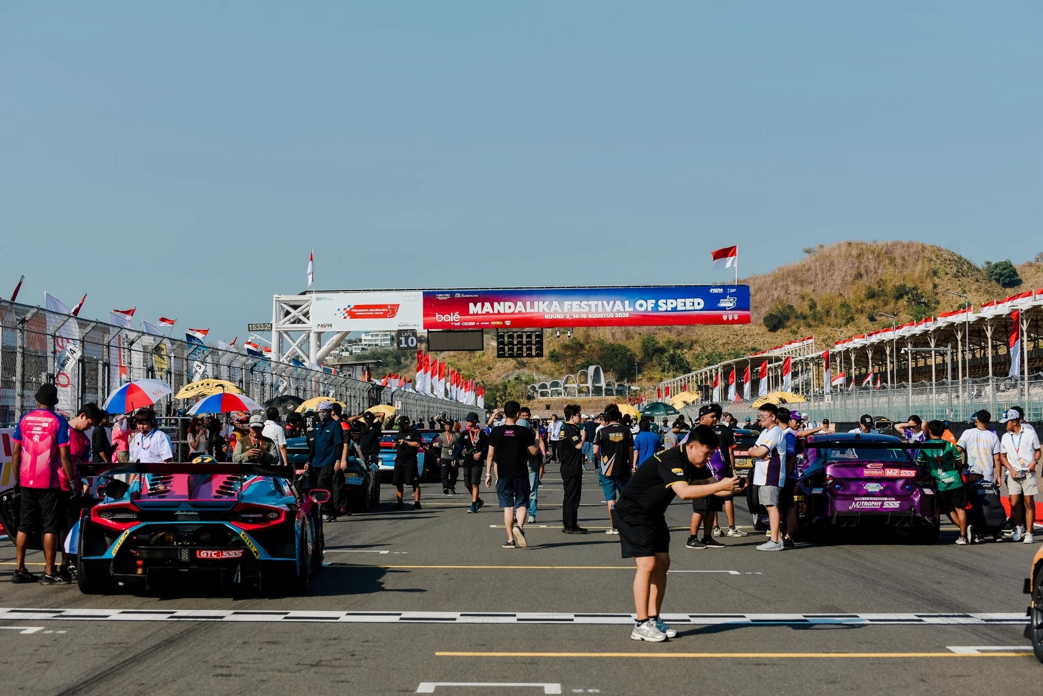 The starting grid of Superstars Sportscar Series in Mandalika International Street Circuit with people able to get close to the cars.