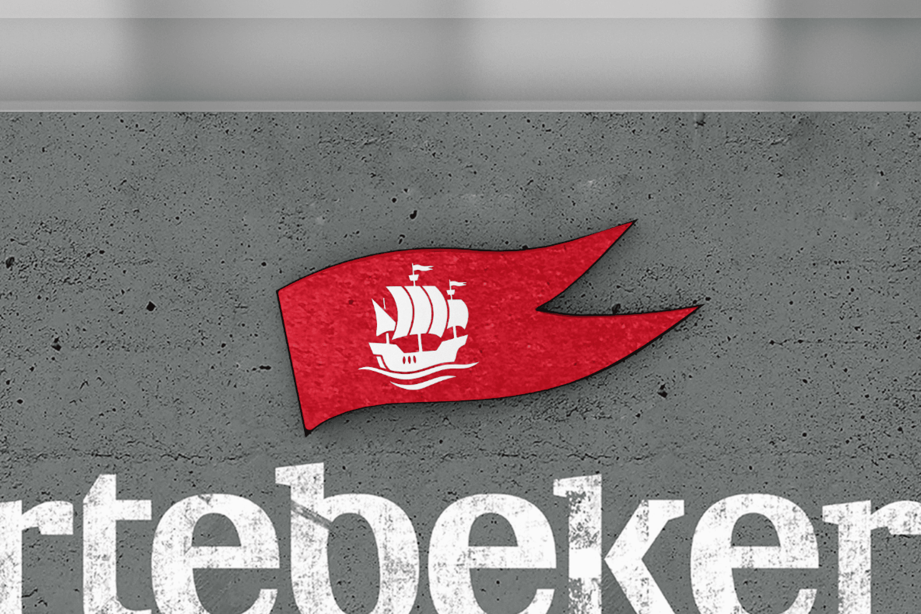 Red flag with white ship icon and part of white text on gray surface.