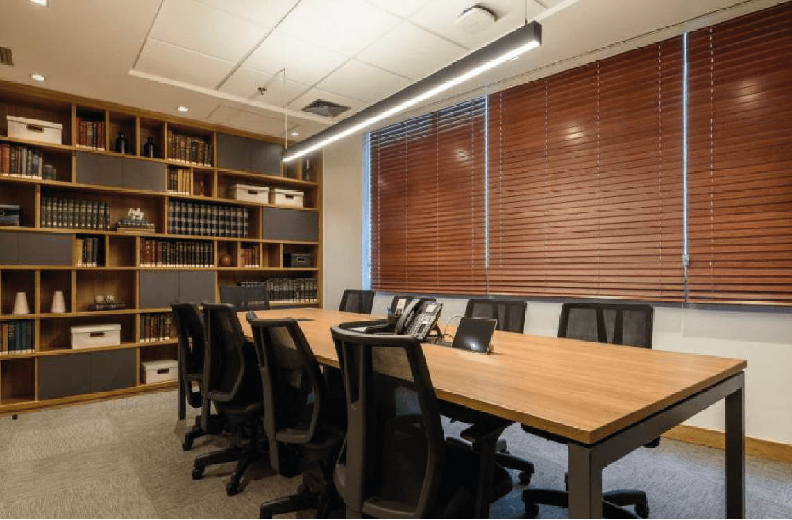 Beige interior with natural stone walls, sunlight, and geometric shadows over a calm water pool.