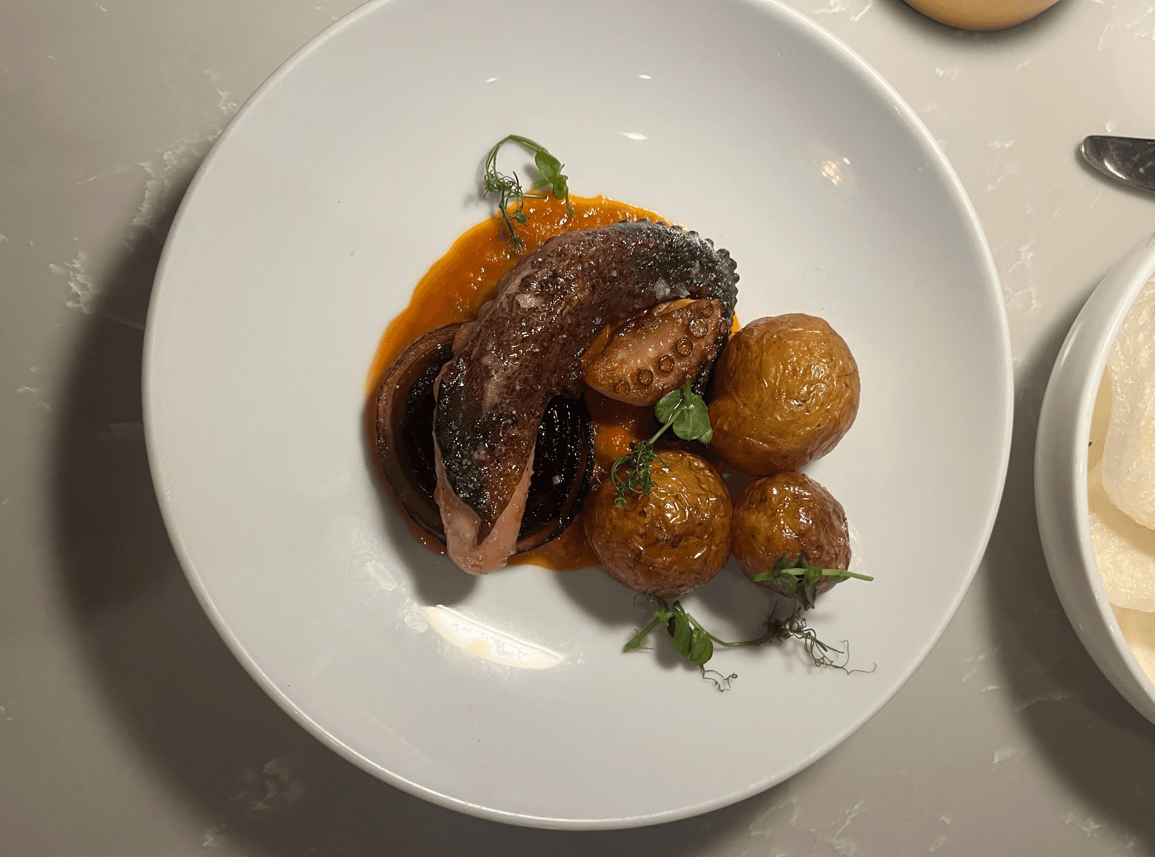 Grilled octopus delicately plated with golden beets, chèvre, grapefruit segments, and crushed pistachios—an elegant, colorful presentation from Bistronomy by Nico.