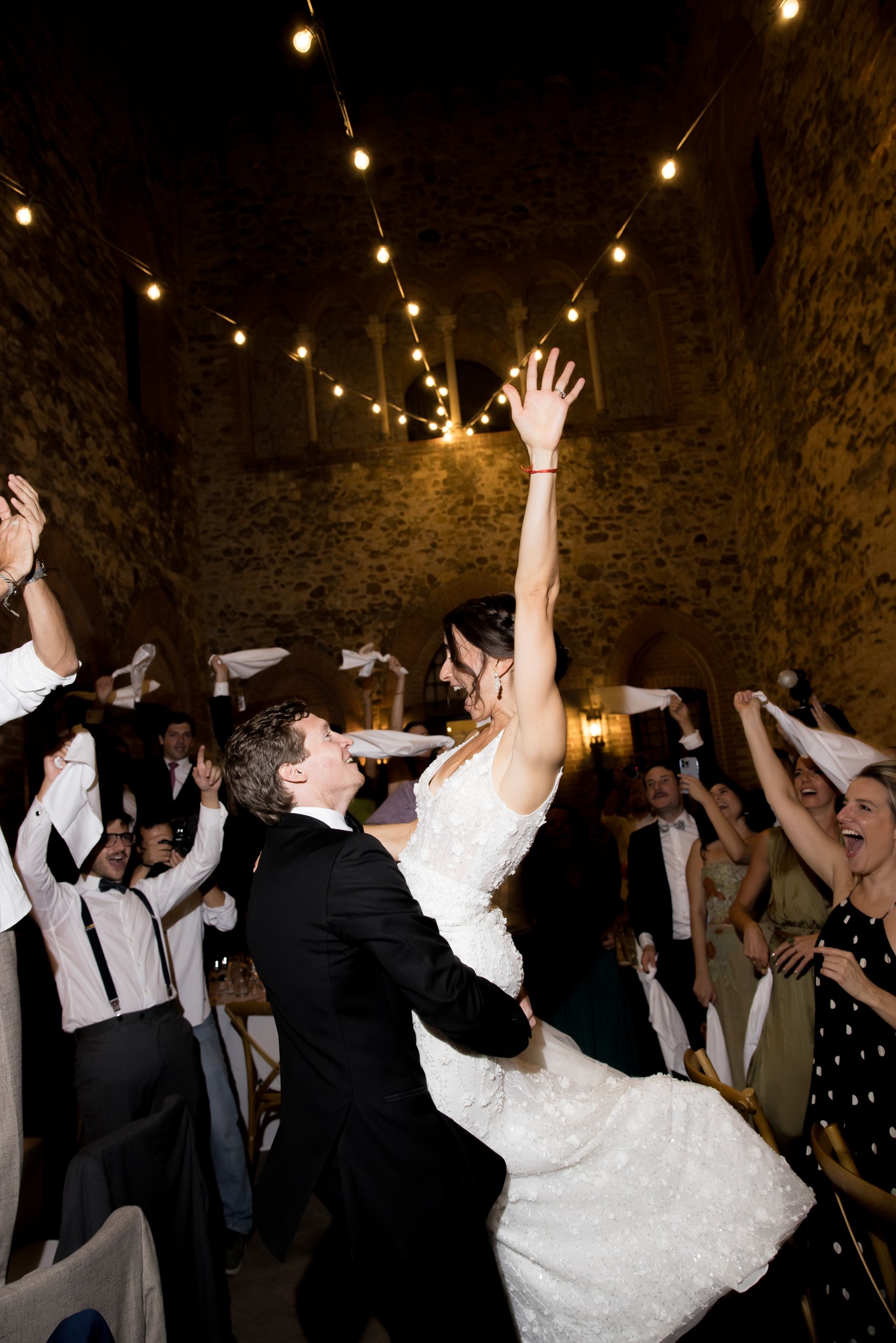 Sposa lancia il bouquet al ricevimento al Castello di Tabiano, ospiti circondati da luci calde in sala storica