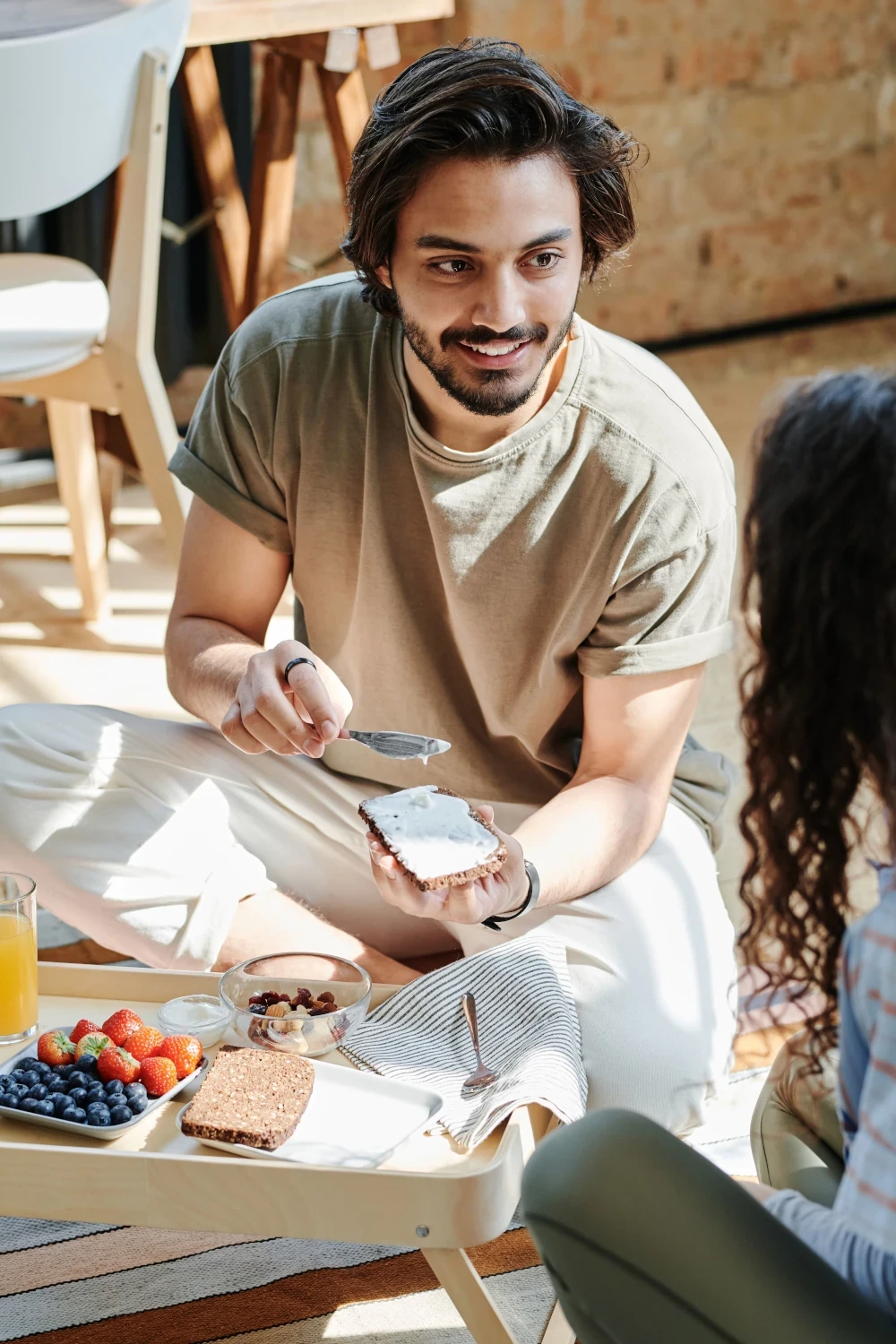 Man preparing food and chatting with someone during a relaxed meal at home.