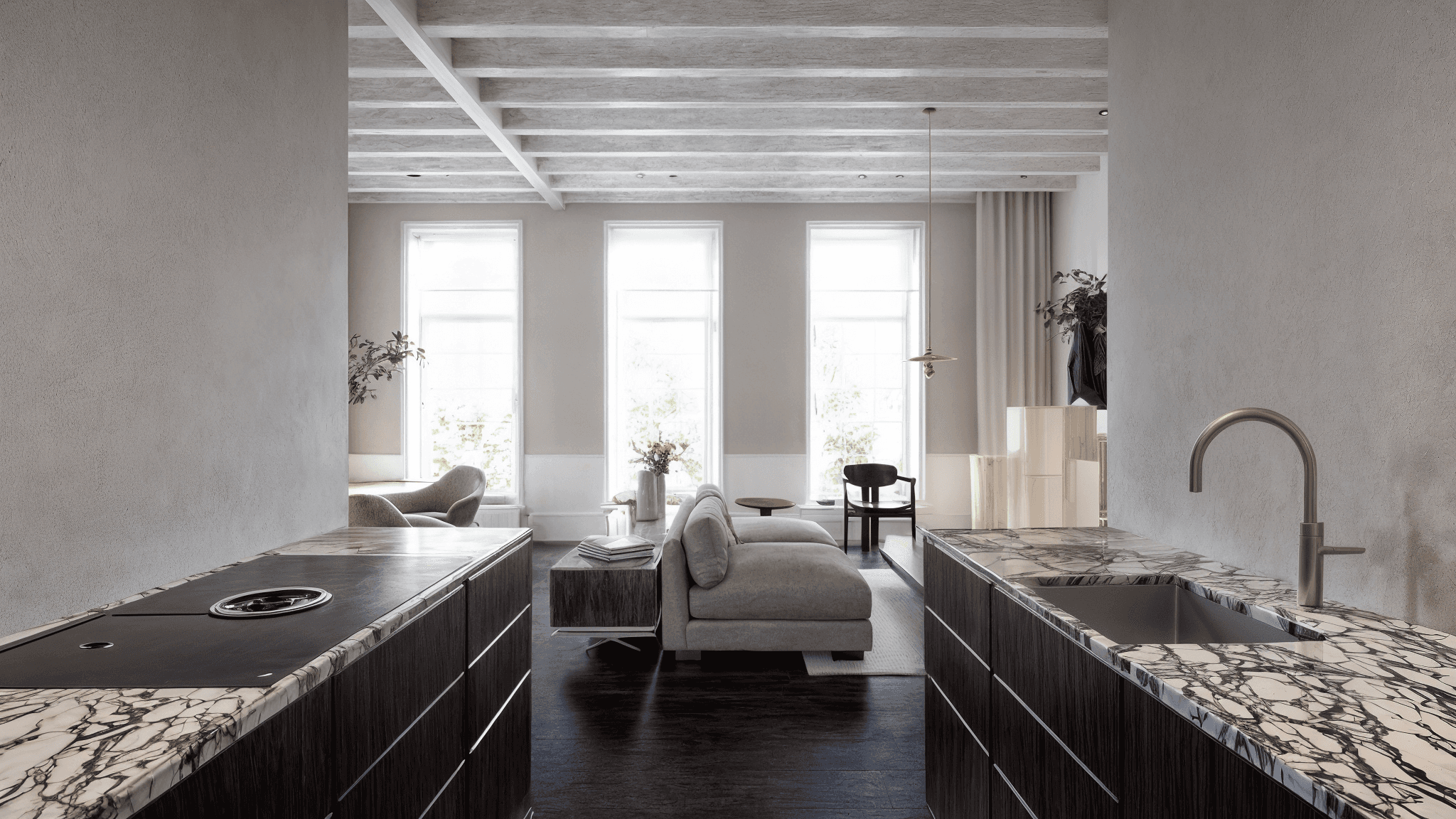 Woonruimte met bank aan weerszijden en hoge ramen met gordijnen in lichte tinten.