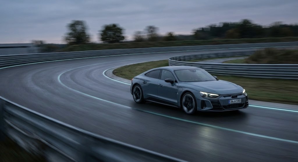 Moderne grå elbil i bevegelse på en våt racerbane, fotografert i en dynamisk sving med fokus på fart og kjøreglede