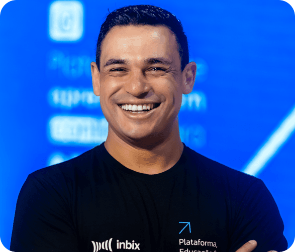 Man smiling in a black Inbix t-shirt, standing with a blue background displaying educational platform elements.
