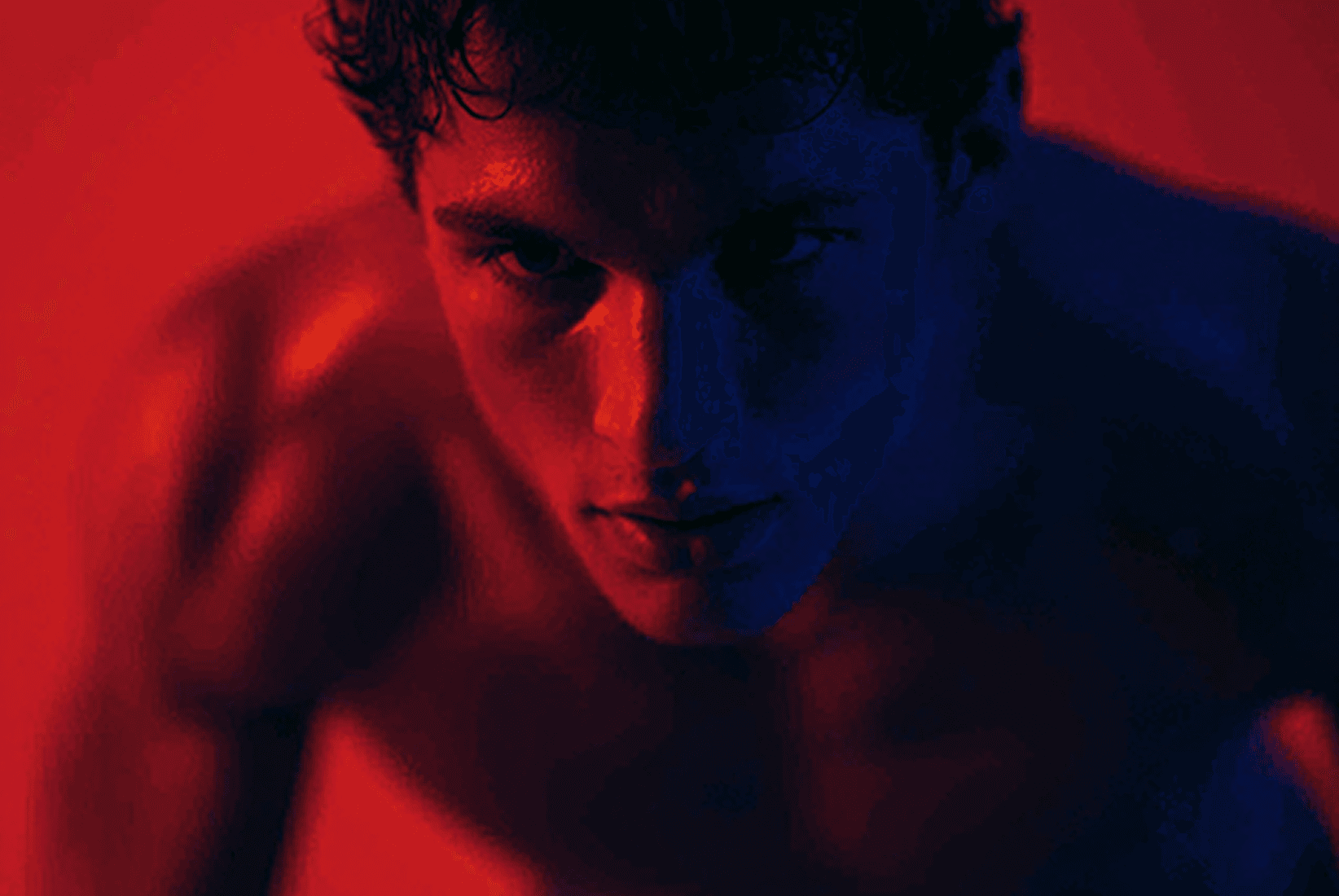 Man's determined expression under dramatic red and blue lighting.