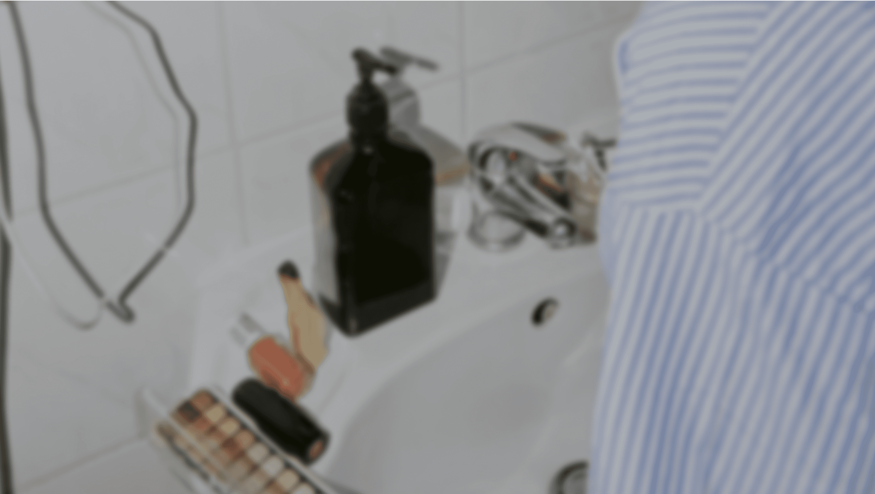 An abstract, out-of-focus image showing various personal care and grooming items on a bathroom counter or shelf.