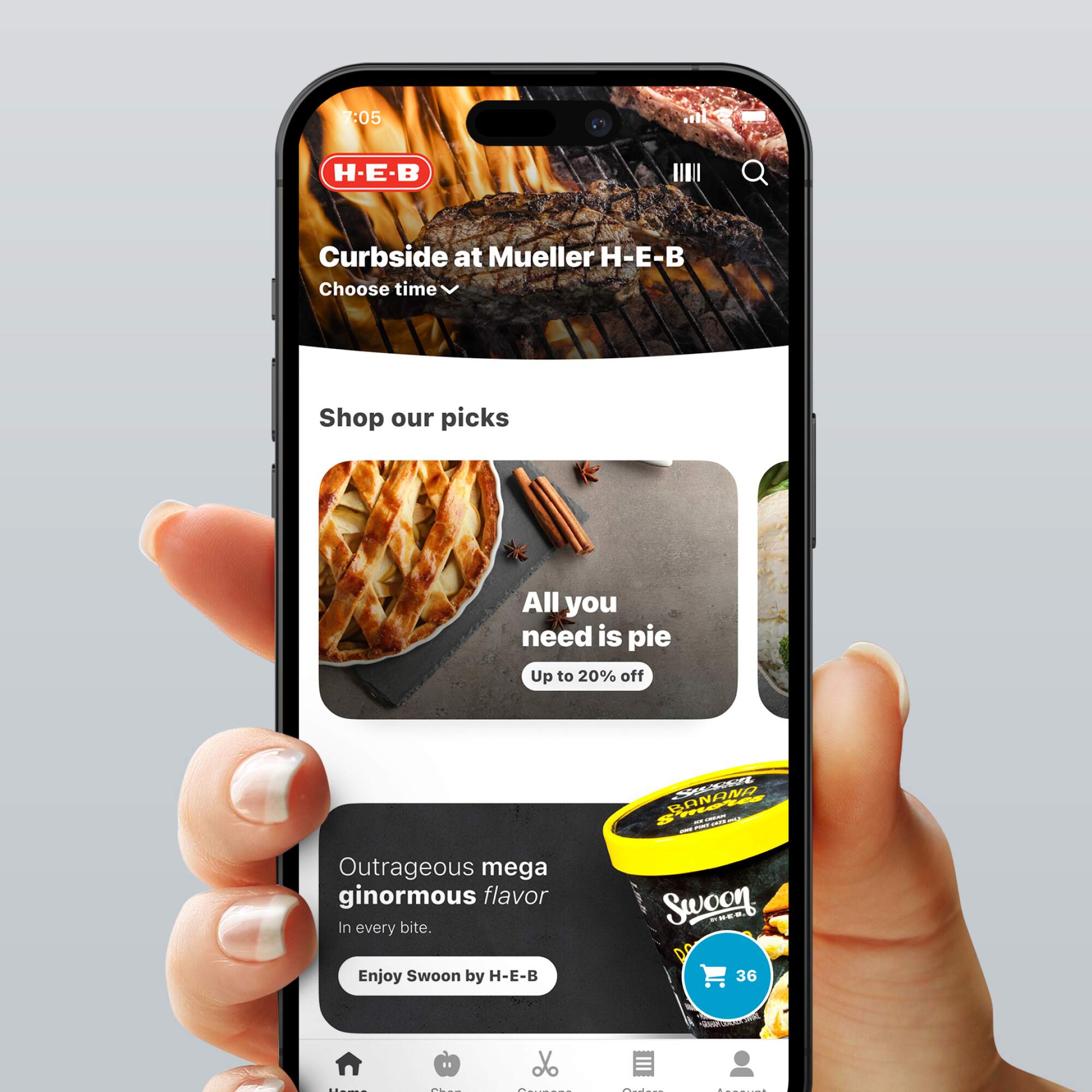 Hand holding a smartphone displaying the H-E-B app home screen with options for curbside pickup, featured items, and promotions.