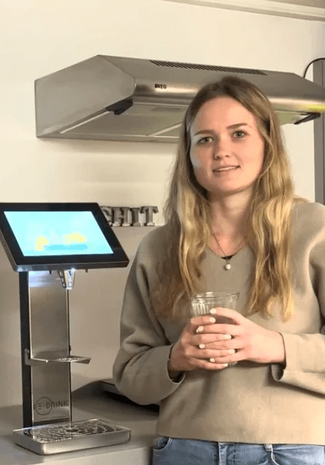 Frau steht zufrieden vor dem Redrink dispenser mit eine getränk in der hand