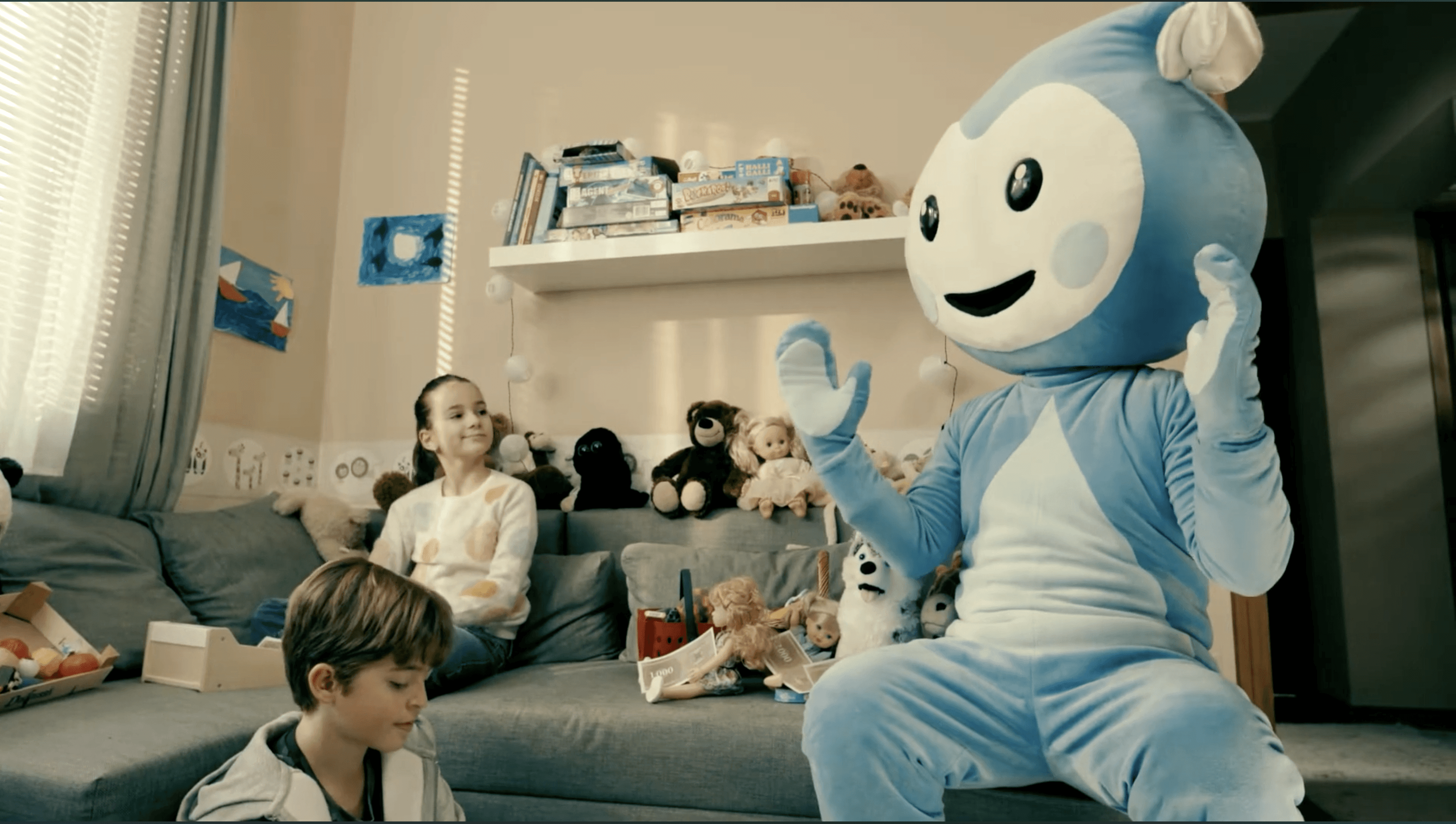 Cseppbarát kékl kabalafigurája a nappaliban magyaráz a gyerekeknek.