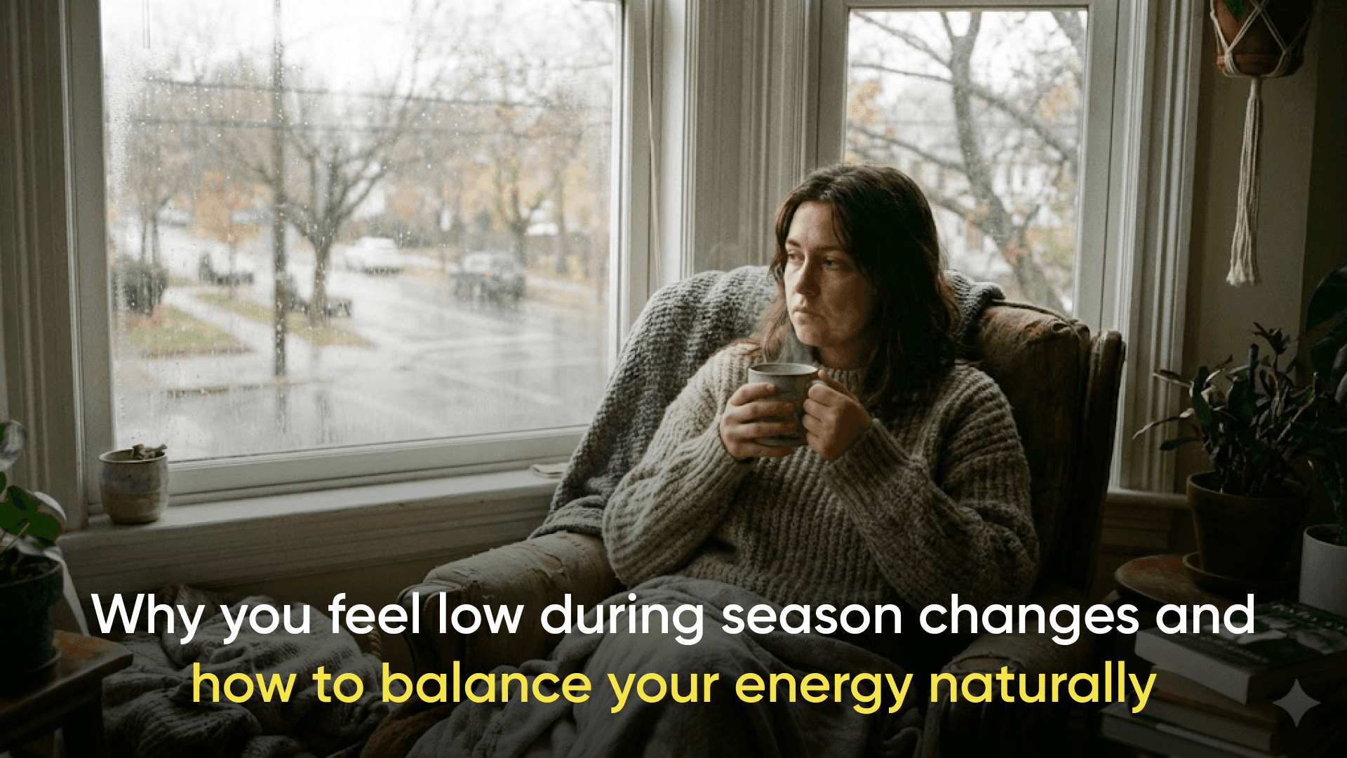 Person sitting by a window on a rainy day holding a warm cup of tea, looking thoughtful, with the text “Why you feel low during season changes and how to balance your energy naturally” displayed on the image.