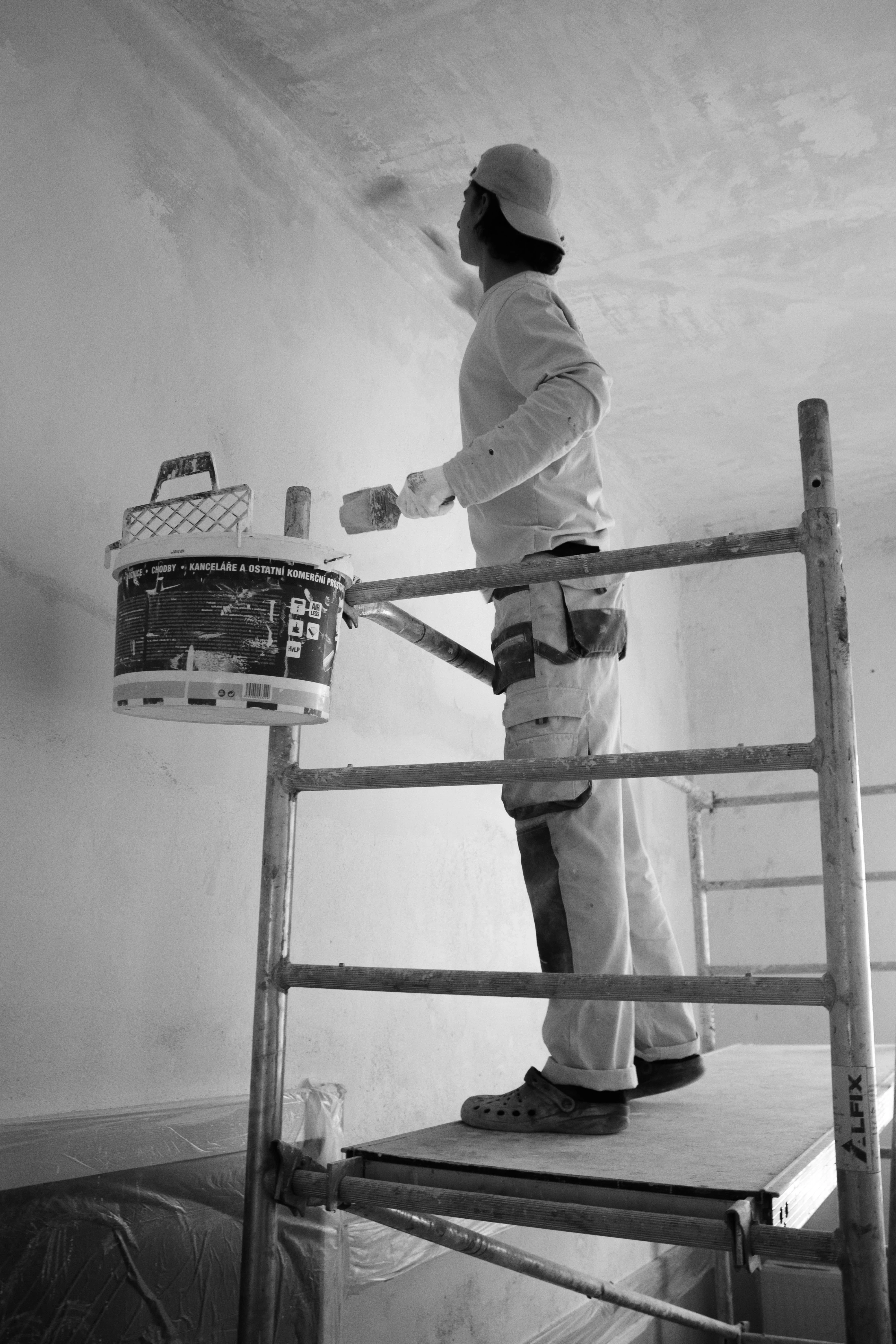 a man painting a wall with a paint roller