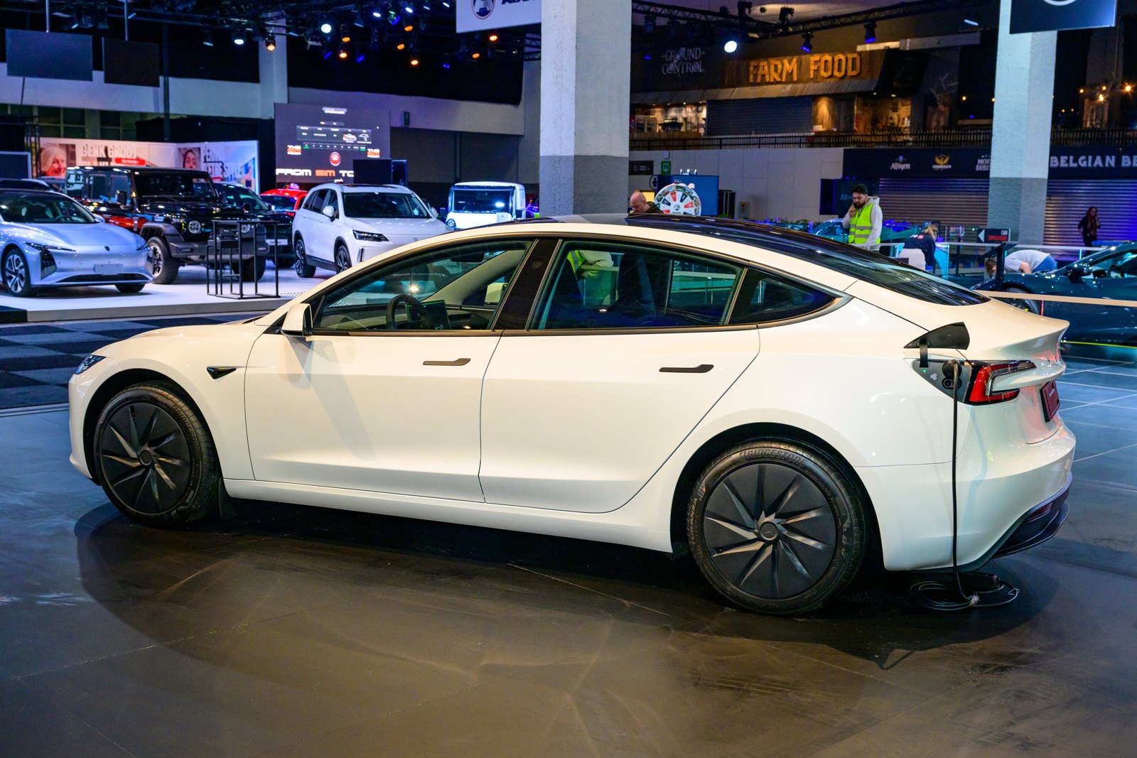 A white Tesla Model 3 parked on a showroom floor.