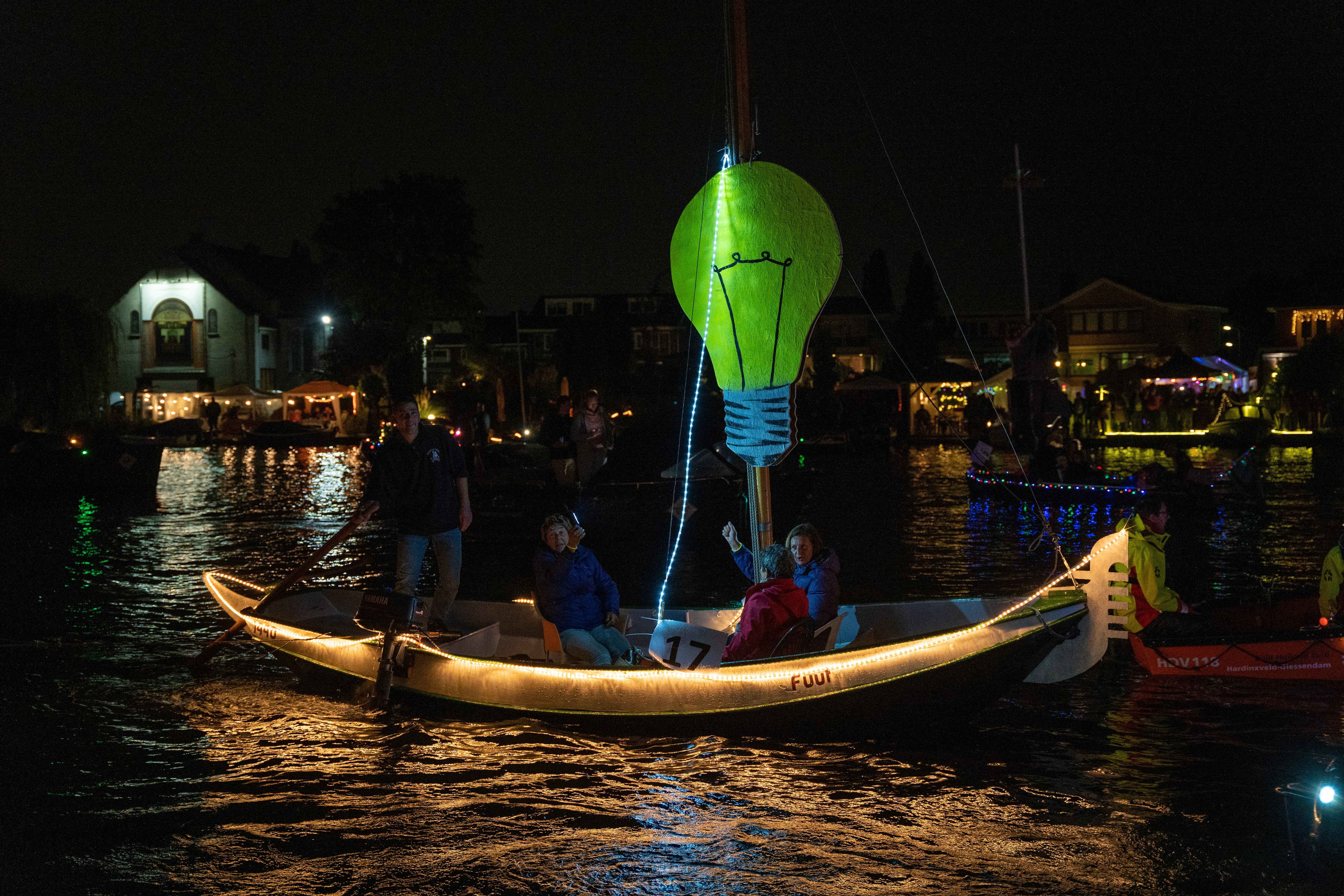 A volleyball player in a black uniform jumping high to spike the ball at the net while opponents attempt to block.