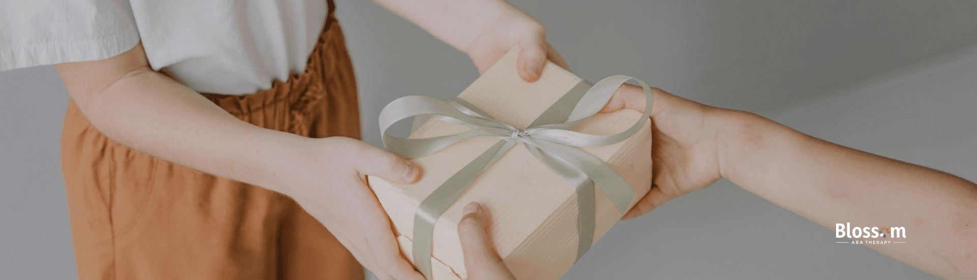 Hands of children with autism exchanging a gift wrapped with ribbon, showing affection in Virginia.