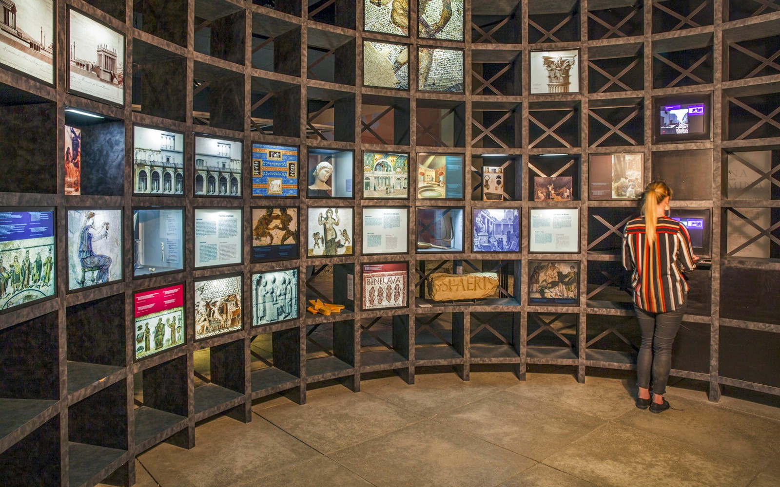 Exhibit at Pont du Gard museum with historical displays and visitor interacting with a screen.